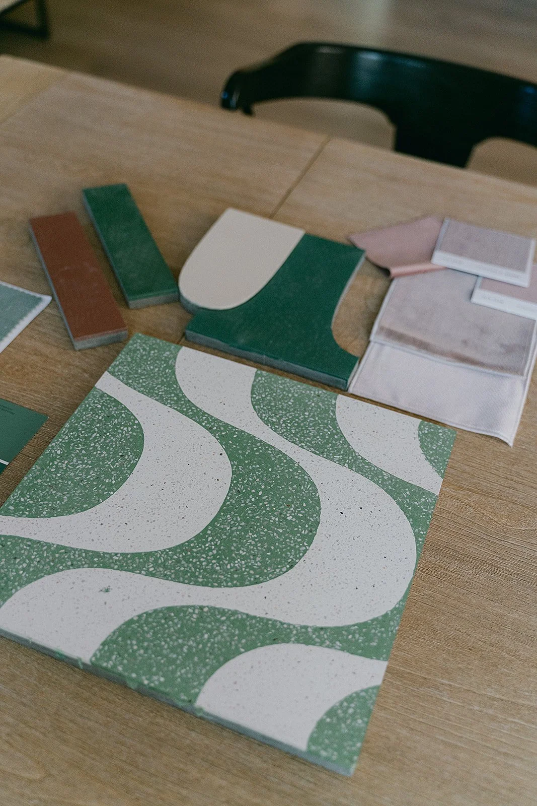 Sample tiles and fabric swatches for interior design on a wooden table.