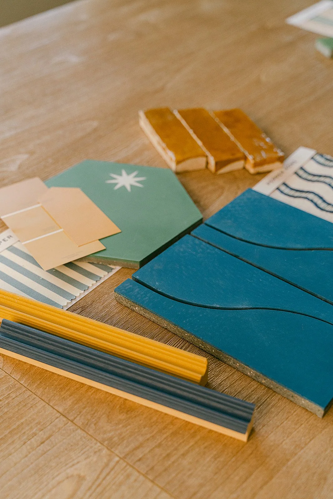 Color samples and tiles on a wooden table, including blue, yellow, green, black, and brown colors, with some pattern samples.