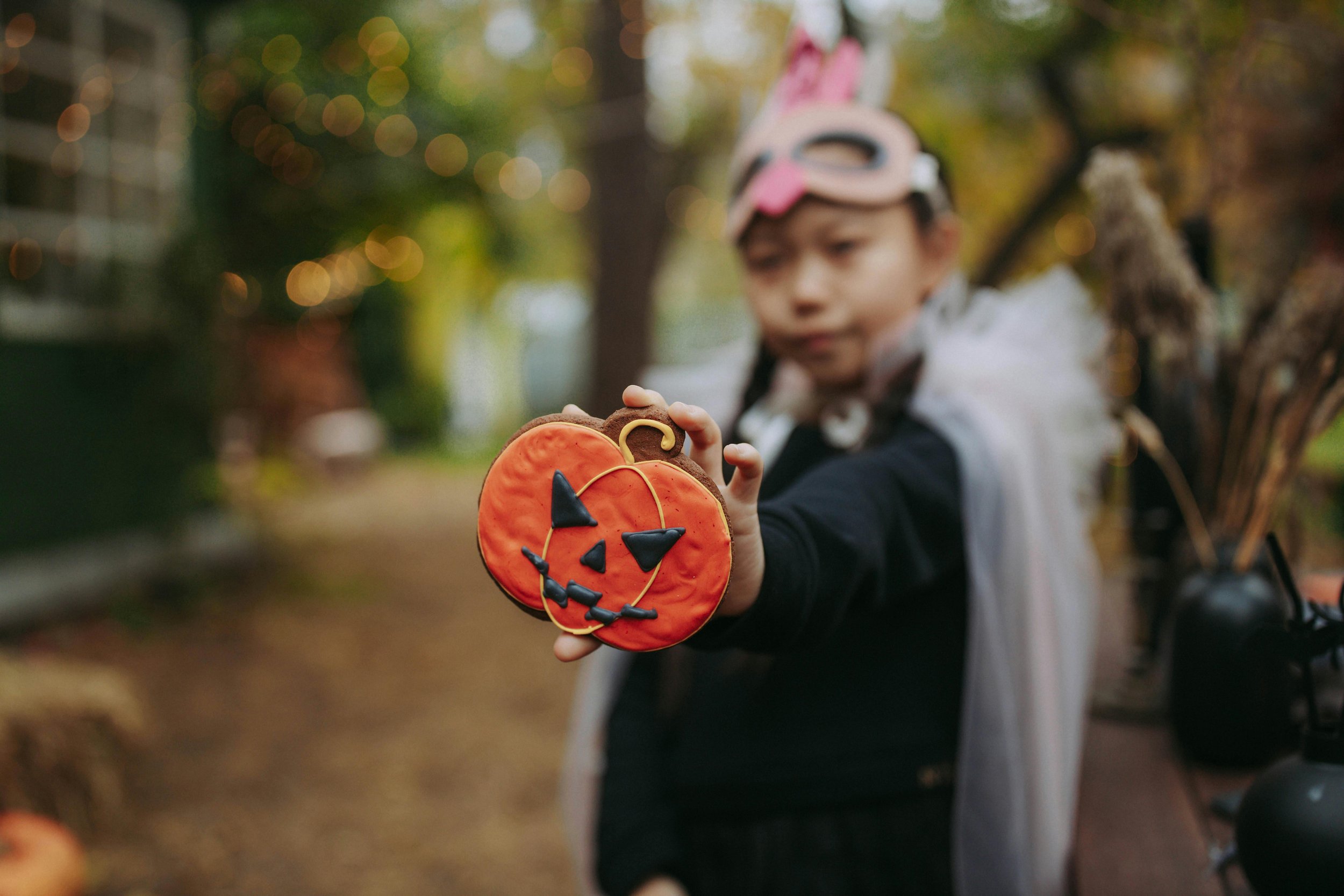 A child holding out a pumpkin cookies