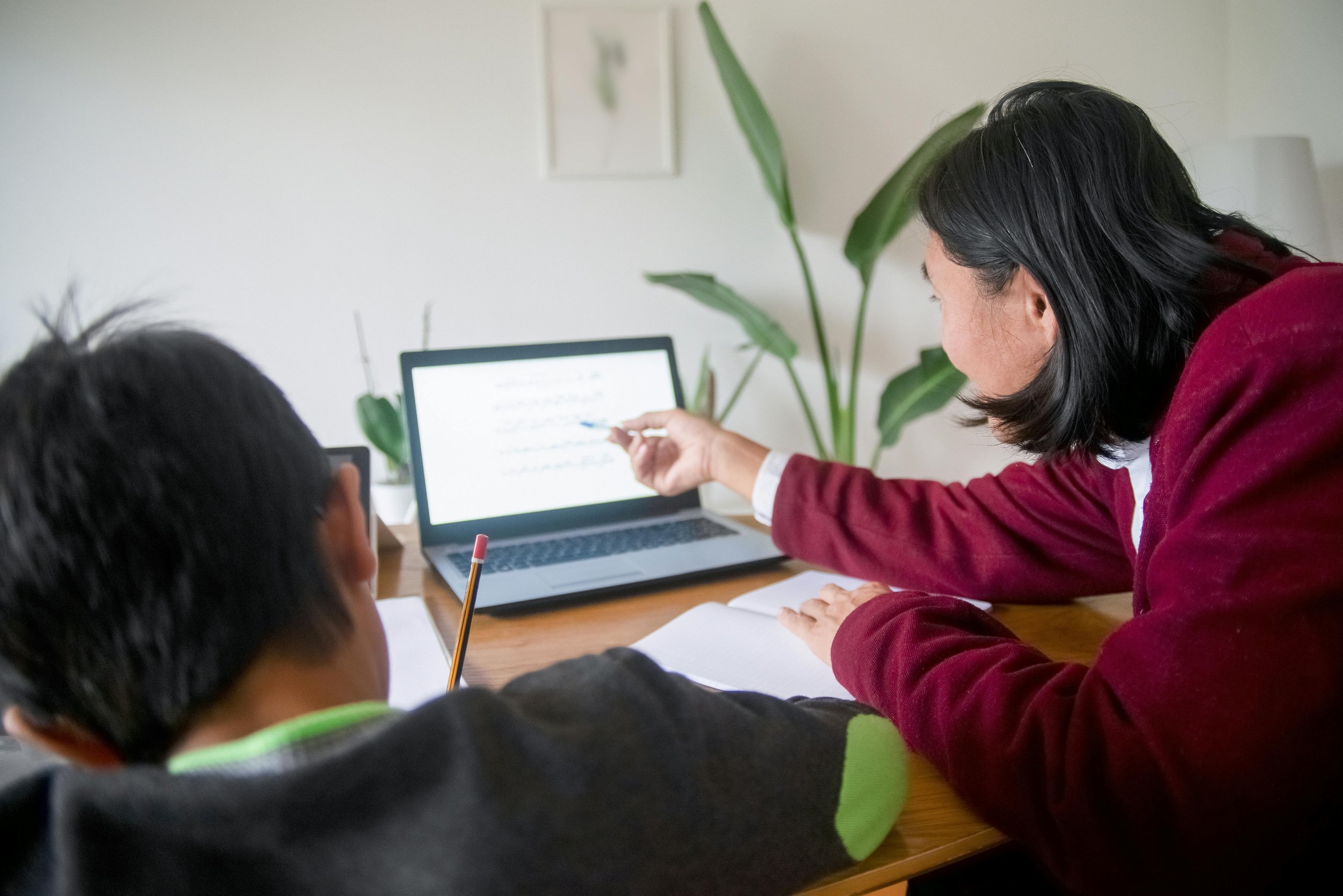 A parent pointing at a screen while they help a student do work