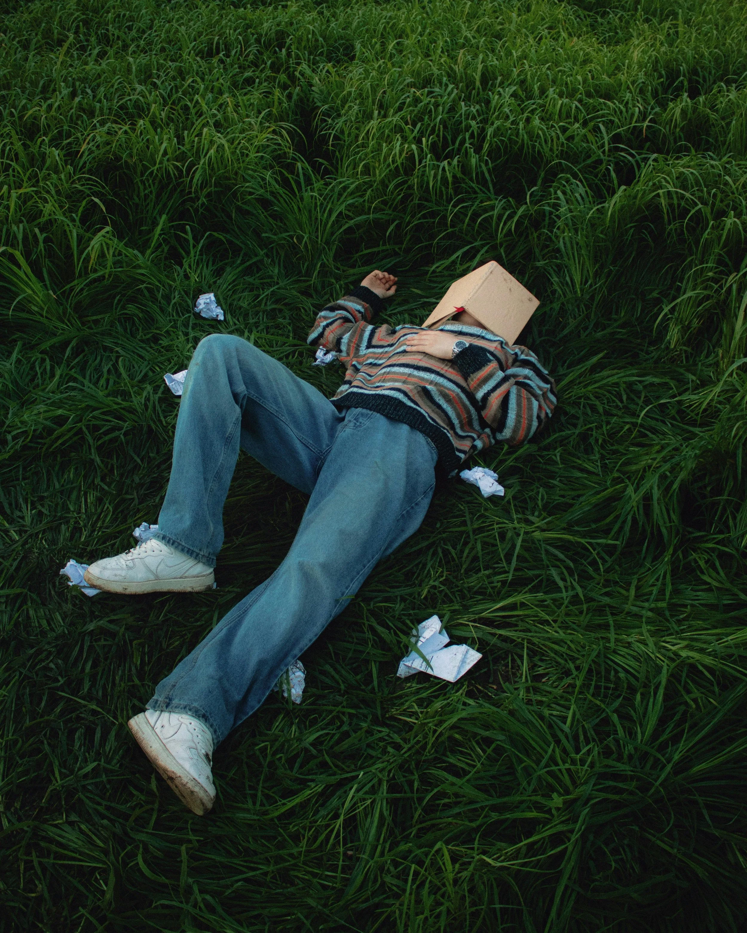 A student laying in the grass with a book on their face
