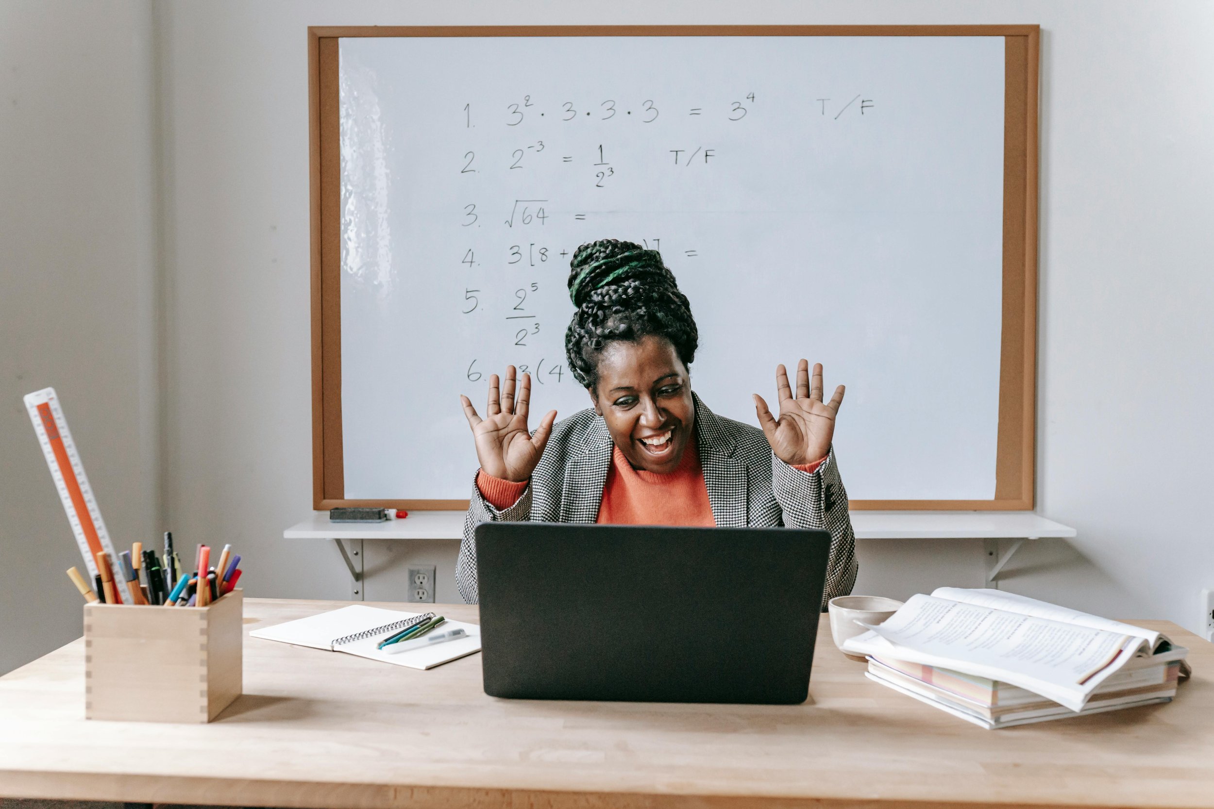 A teacher smiling at a computer screen