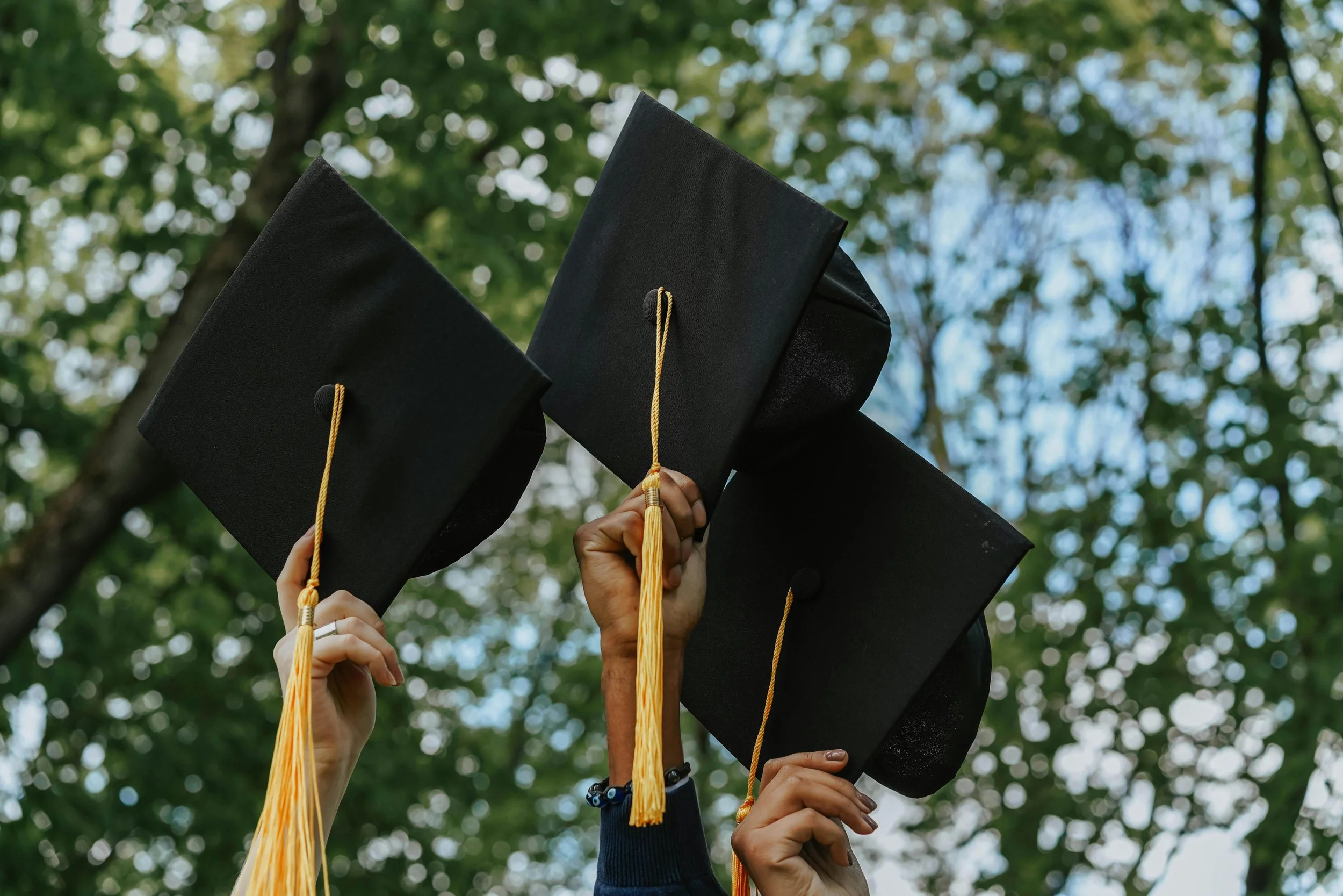 Students holding up graduation caps