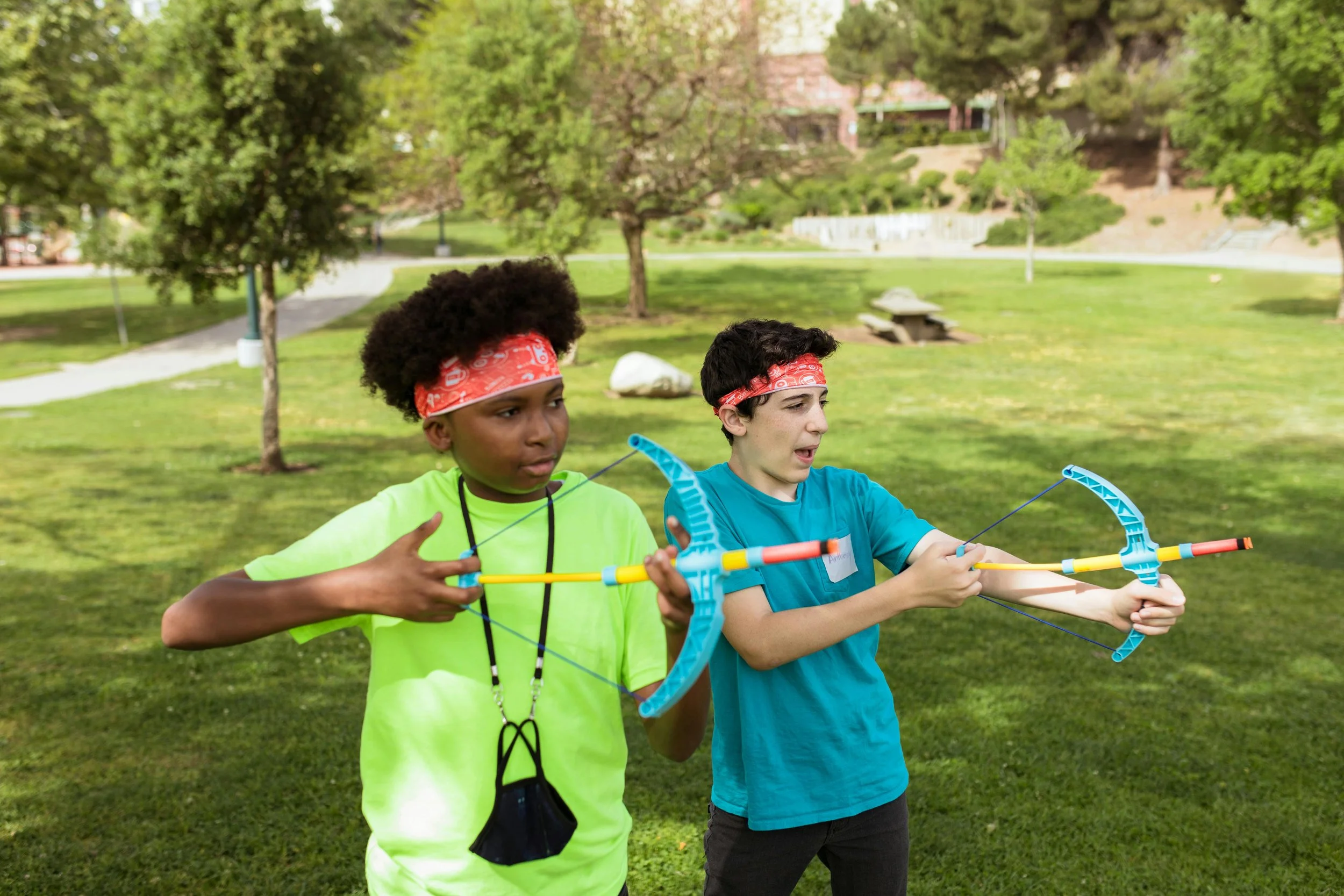 Two kids hold play bows, ready to fire.