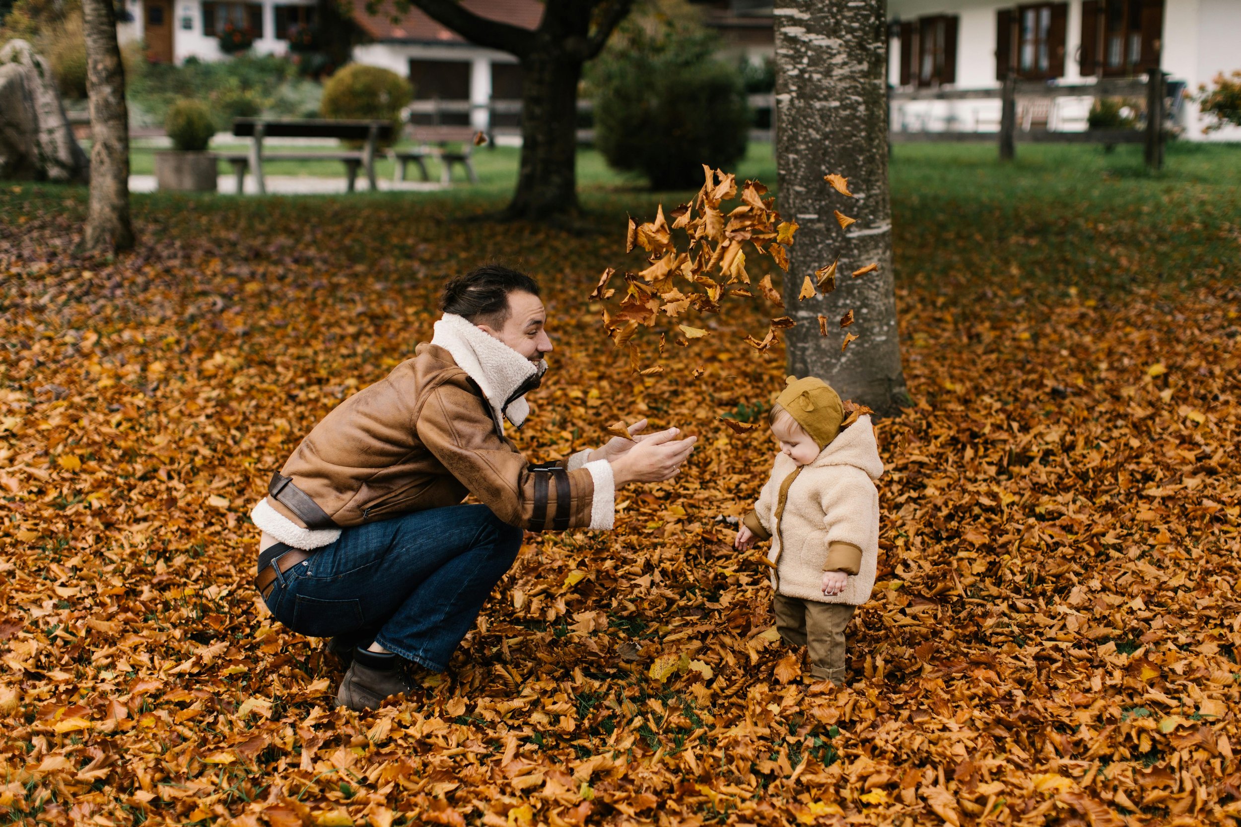 A parent playing in the leaves with their child