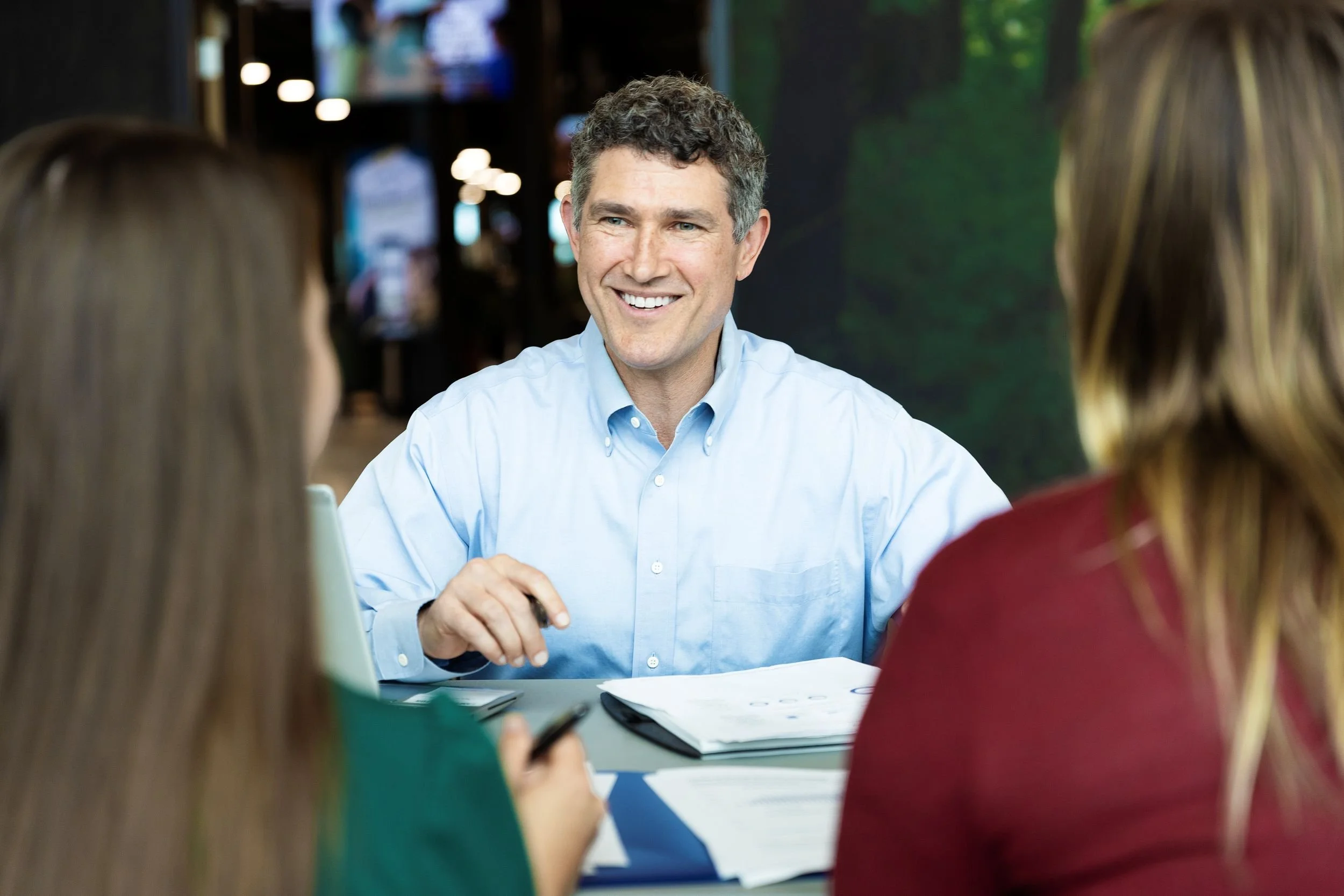 Randy Derenzo in light blue button down shirt meeting with two women clients
