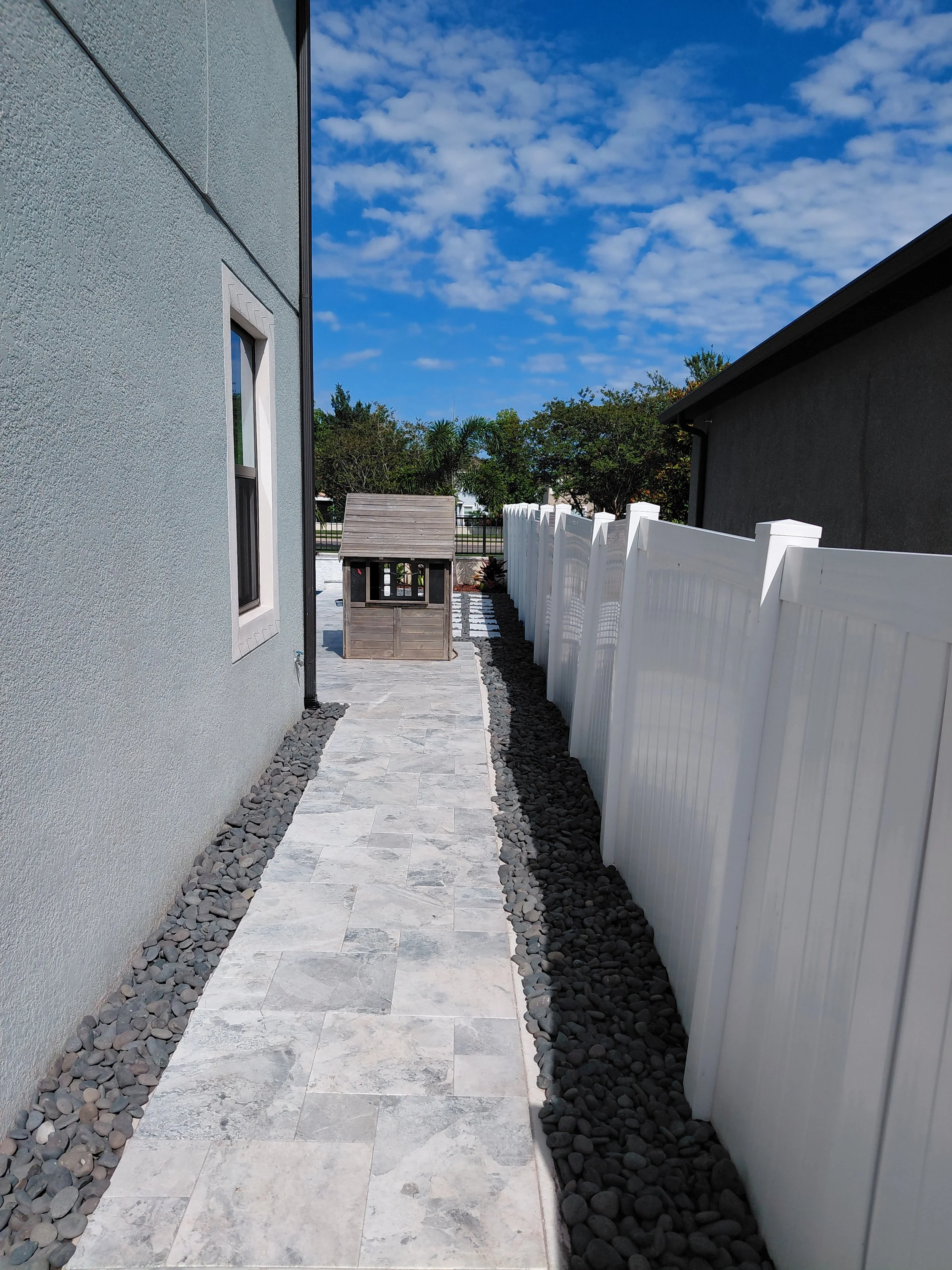 Riverview, FL-Mexican Beach Pebble pathway installation along a side yard corridor. Double-layered landscape fabric underneath ensures long-term weed suppression and a clean low-maintenance finish.