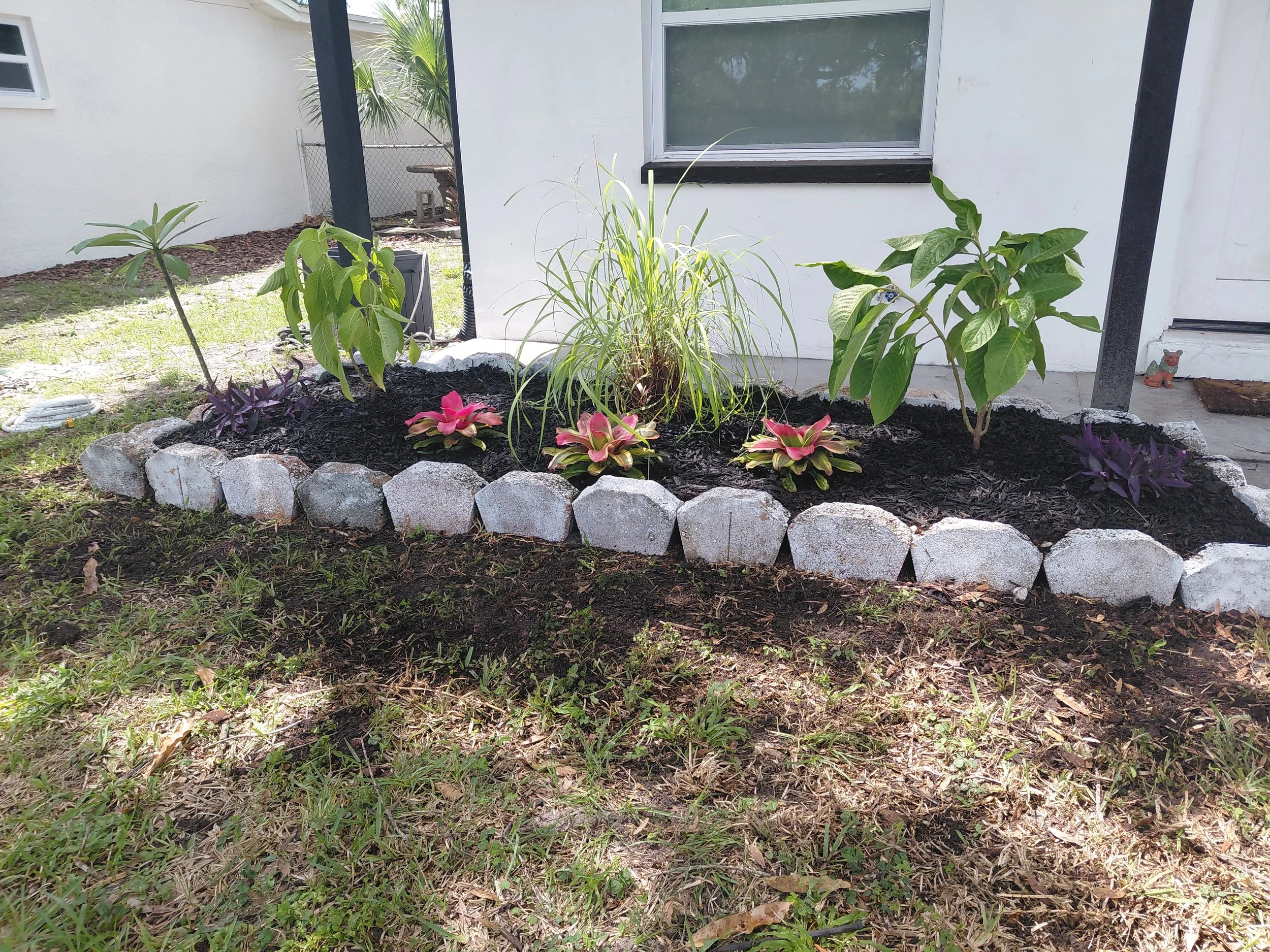 South Tampa, FL-Custom planting bed installation featuring tropical ornamentals, flowering color, and natural stone border edging. Designed to add dimension while using different textured leaves for a unique look.