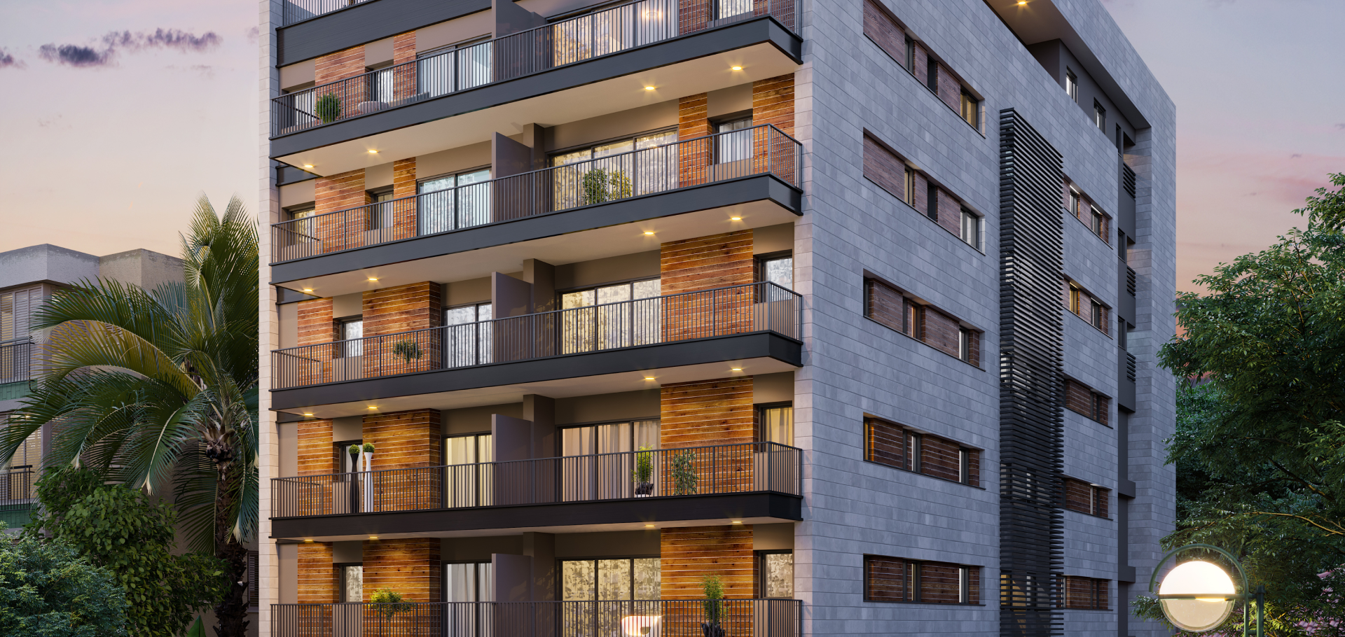 A modern multi-story residential building with balconies, brick and concrete exterior, and lighting at dusk. There are trees and street lamps nearby.
