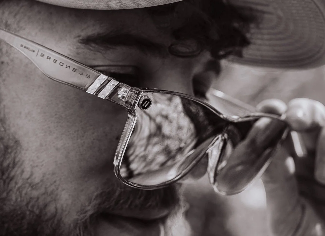 Close-up black and white photo of a person wearing glasses and holding a spoon near their face.