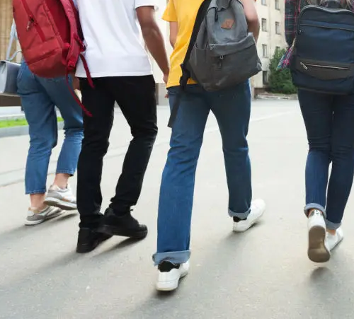 Group of people walking on a city street, carrying backpacks.