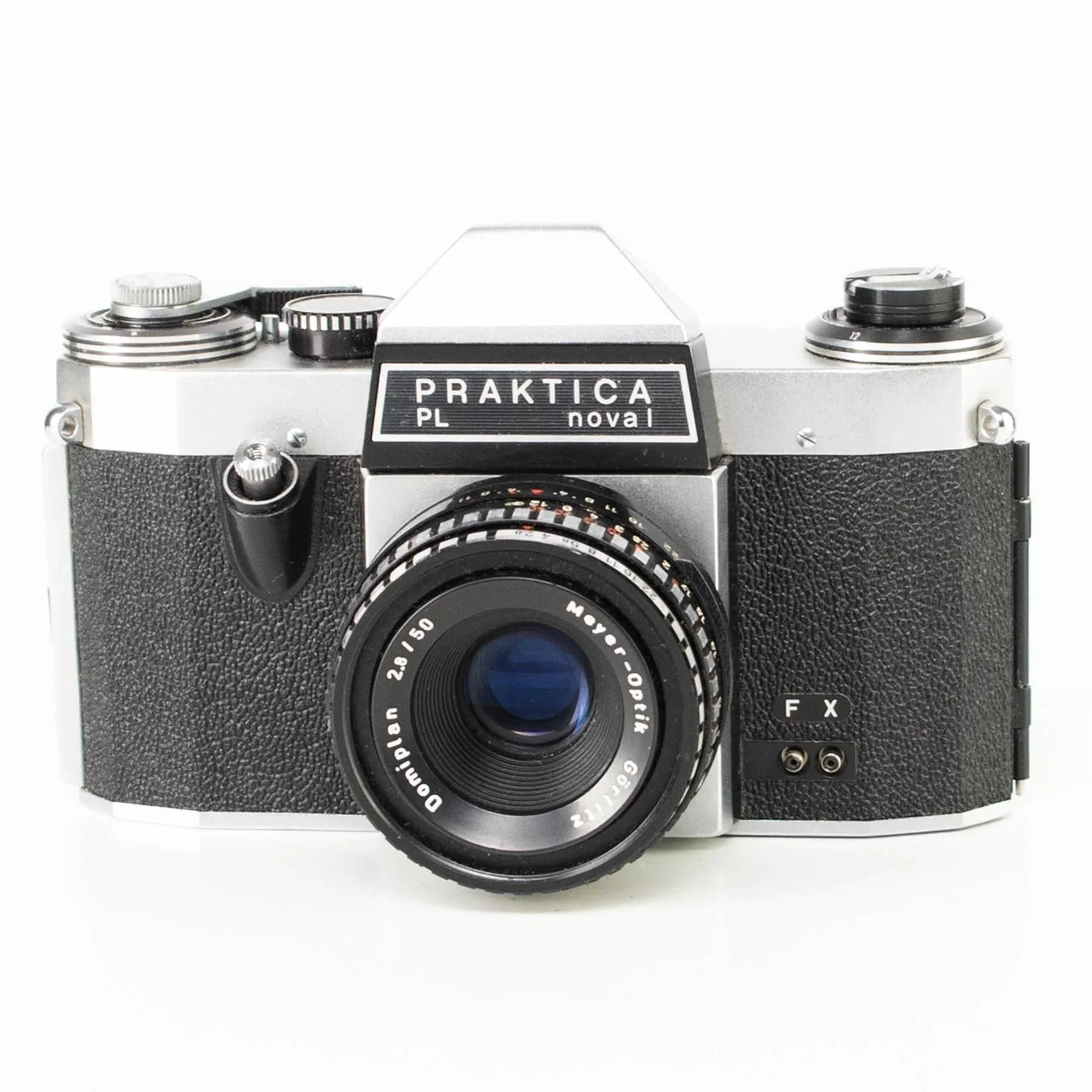 Close-up of Pat Mccarthy's vintage Praktica film camera with a lens, textured black grip, and various dials and buttons, against a white background.