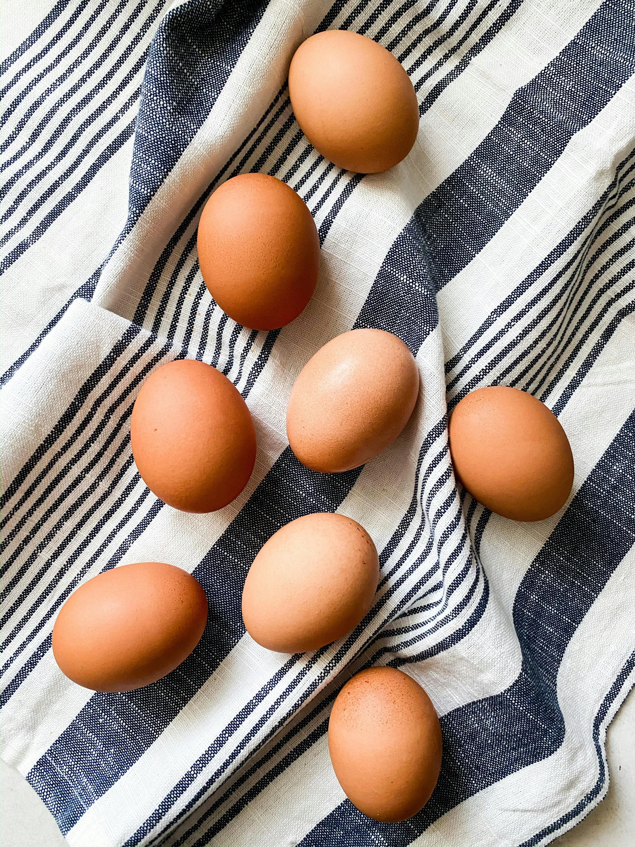 Seks brune egg på en stripete svart-hvit stoffklut.