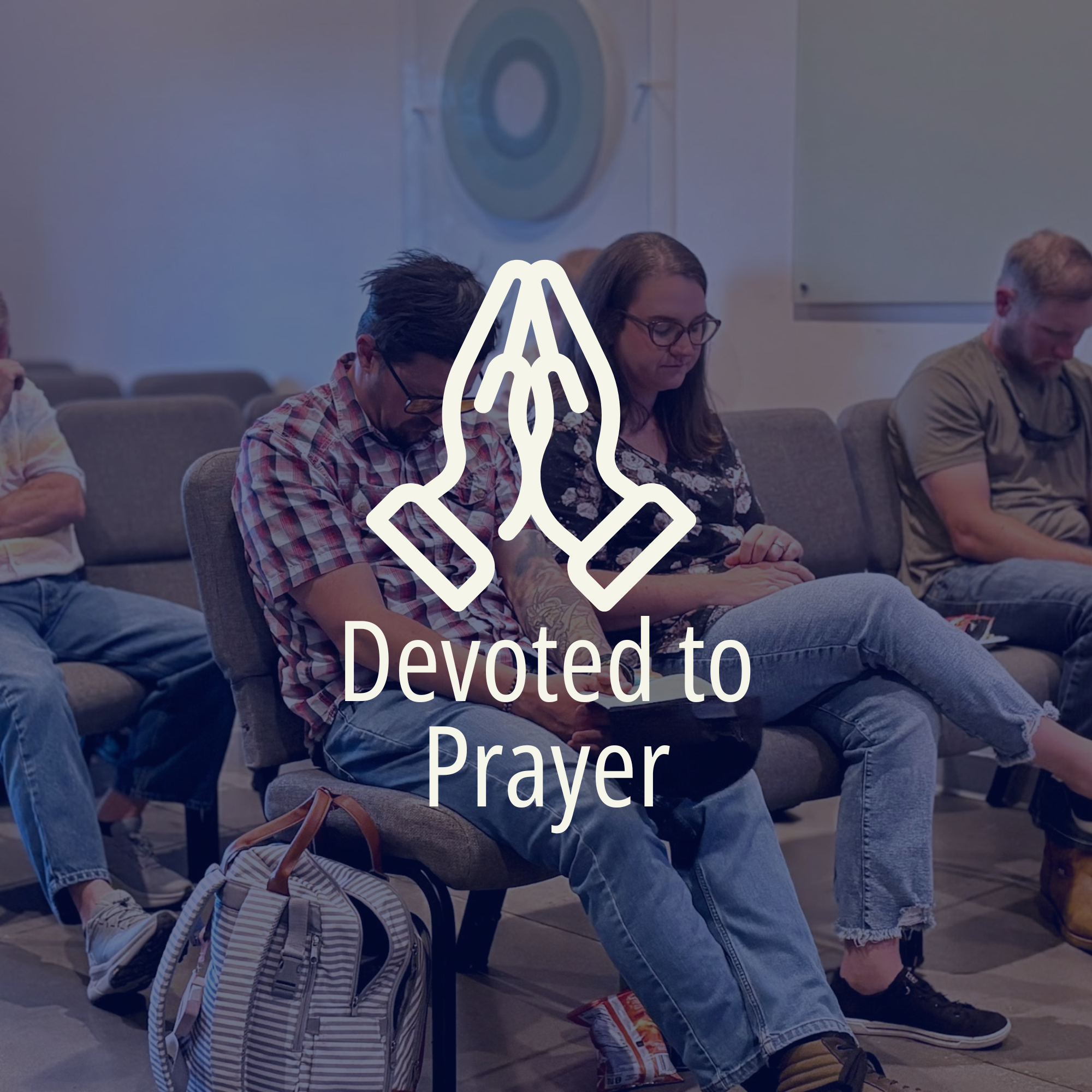 People praying on a church pew with a white altar in the background.