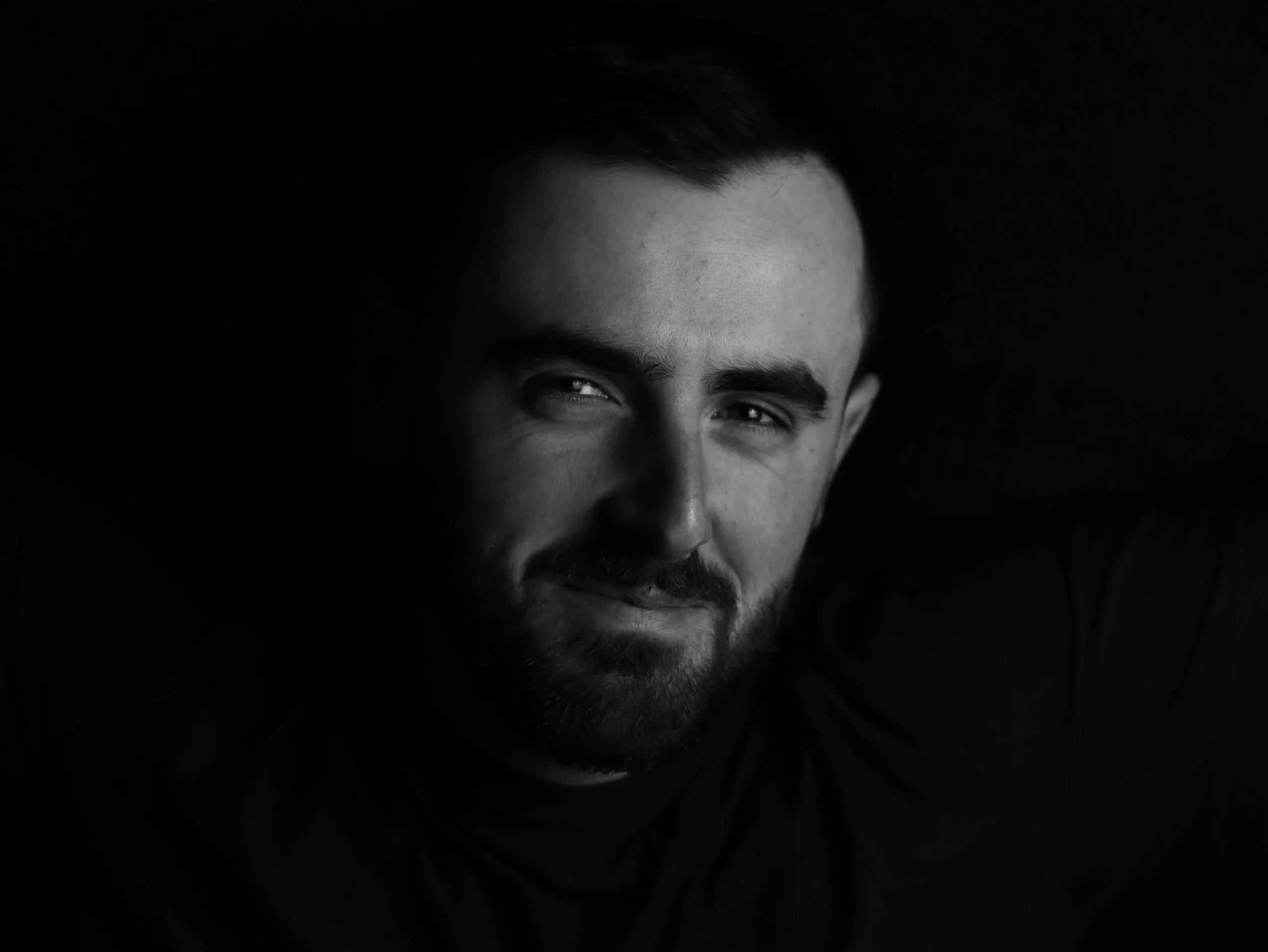 Close-up of a man's face, focusing on his eyes, forehead, and part of his nose, with a dark background.