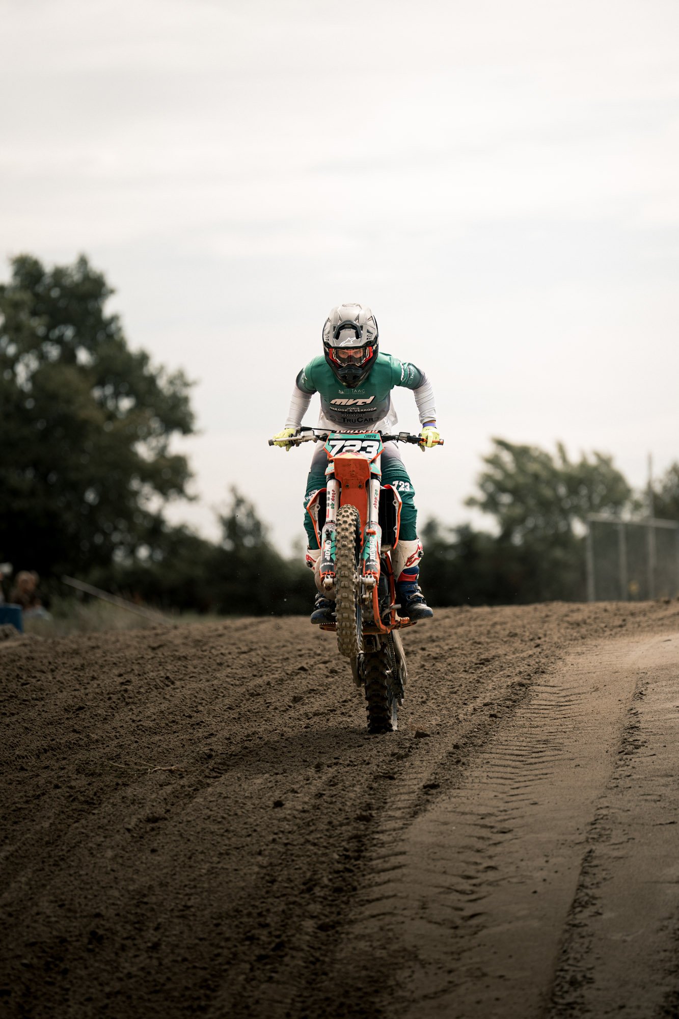 Moter op een off-road motorfiets die een sprong maakt op een zandachtig terrein.