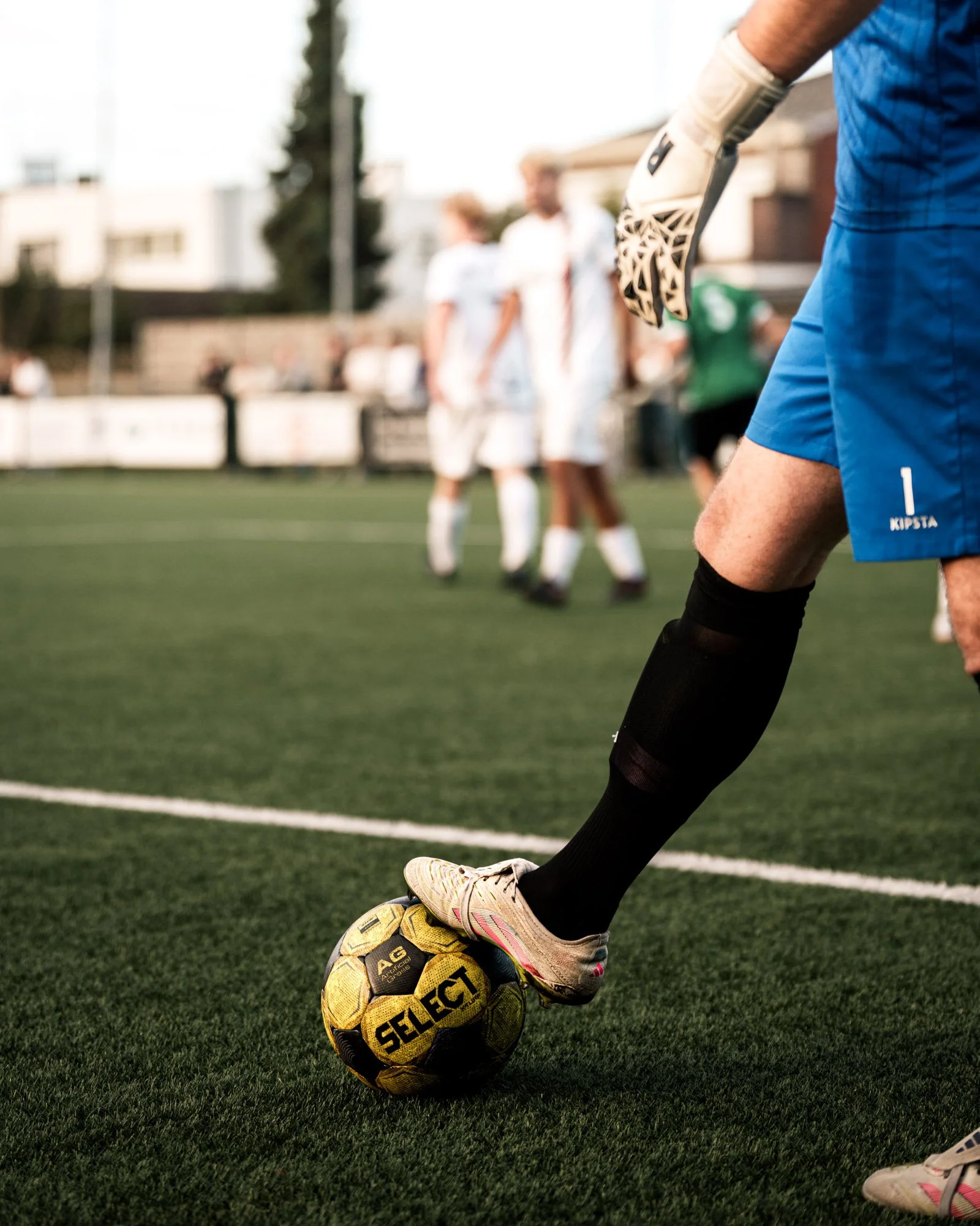 Een voetballer in sportkleding die een voetbal met de voet aanraakt, op een grasveld.