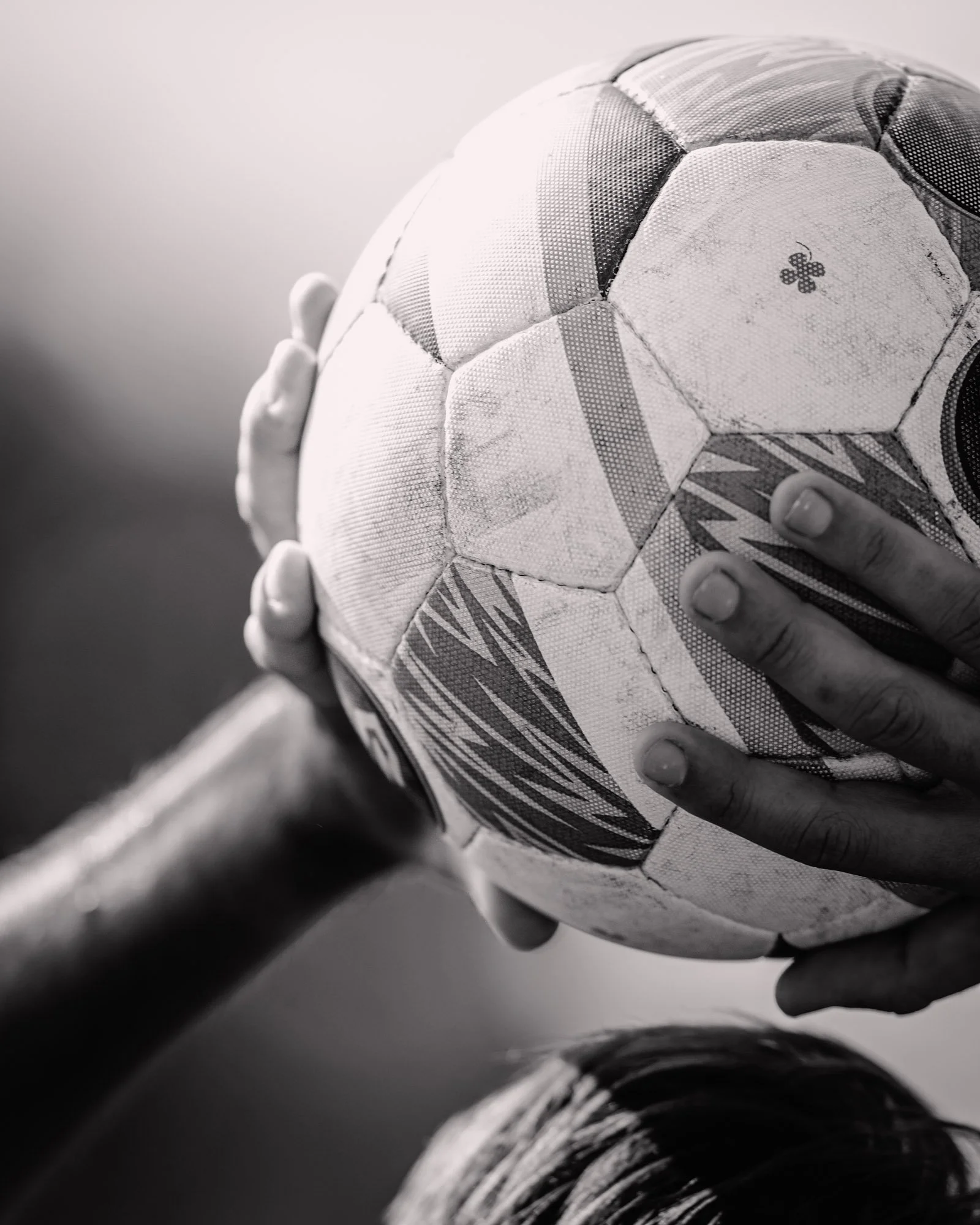 Dichtbij beeld van een voetbal met een hand die het vasthoudt.