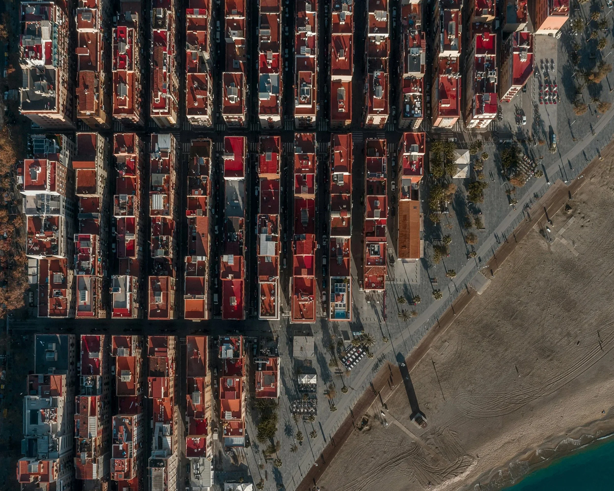 Vista aérea de una ciudad con edificios de techos rojos, calles y árboles, tomada en un día despejado.