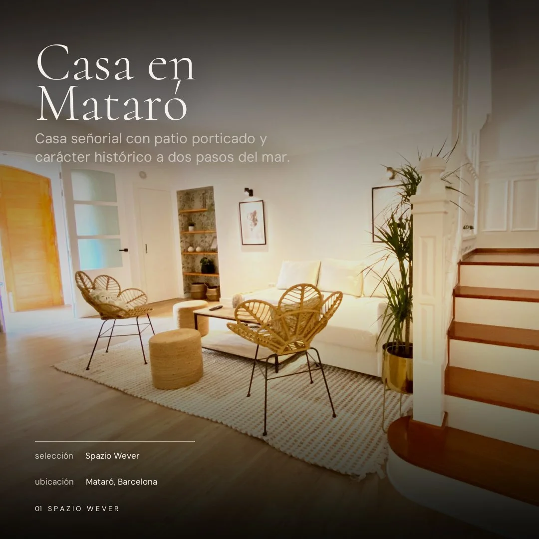 Sala de estar con sillones de mimbre, una mesa de centro, una planta grande y una escalera de madera y blanco. Pantalla con texto promocional para una casa en Mataró, Barcelona.