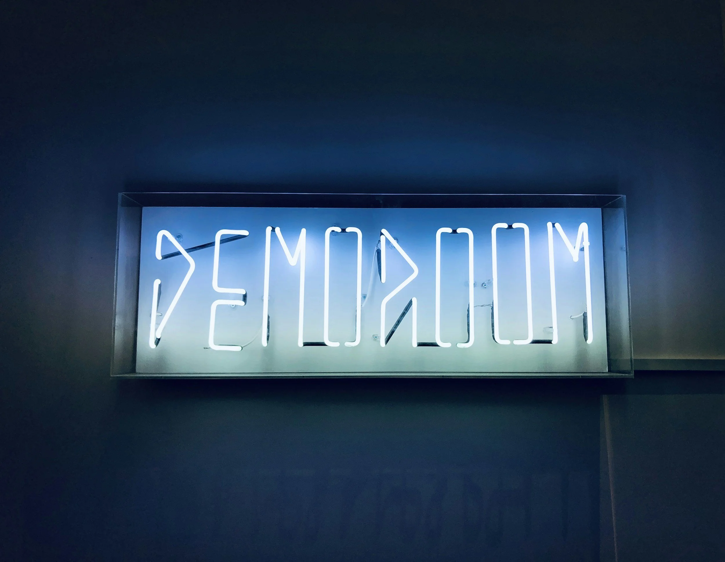 Letreiro de néon retroiluminado com a palavra 'WELLNESS' em letras brancas sobre fundo escuro.