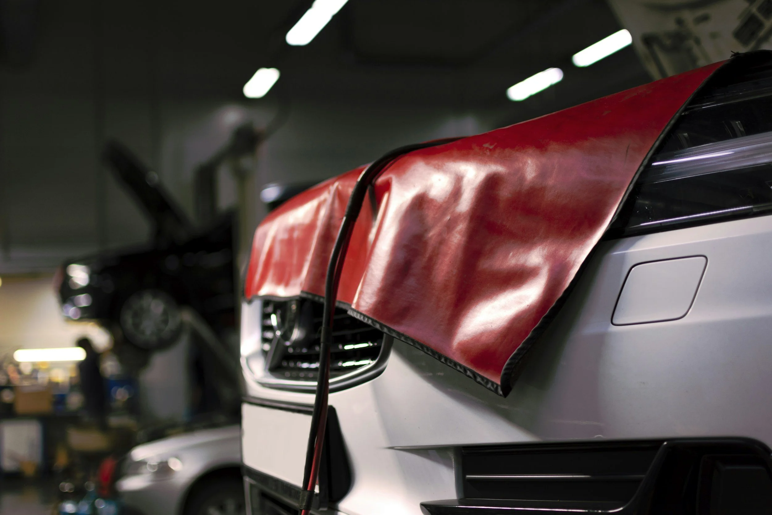Dispositivo vermelho com cabos ligados a um computador portátil num ambiente de garagem ou oficina.
