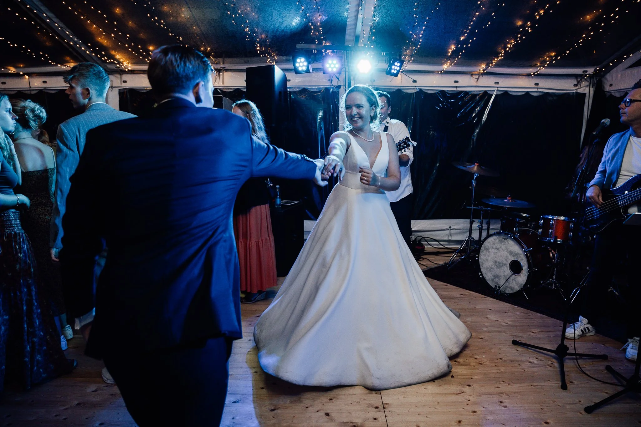 En brud danser med en mand, mens resten af gæsterne ser på under en festlig begivenhed.