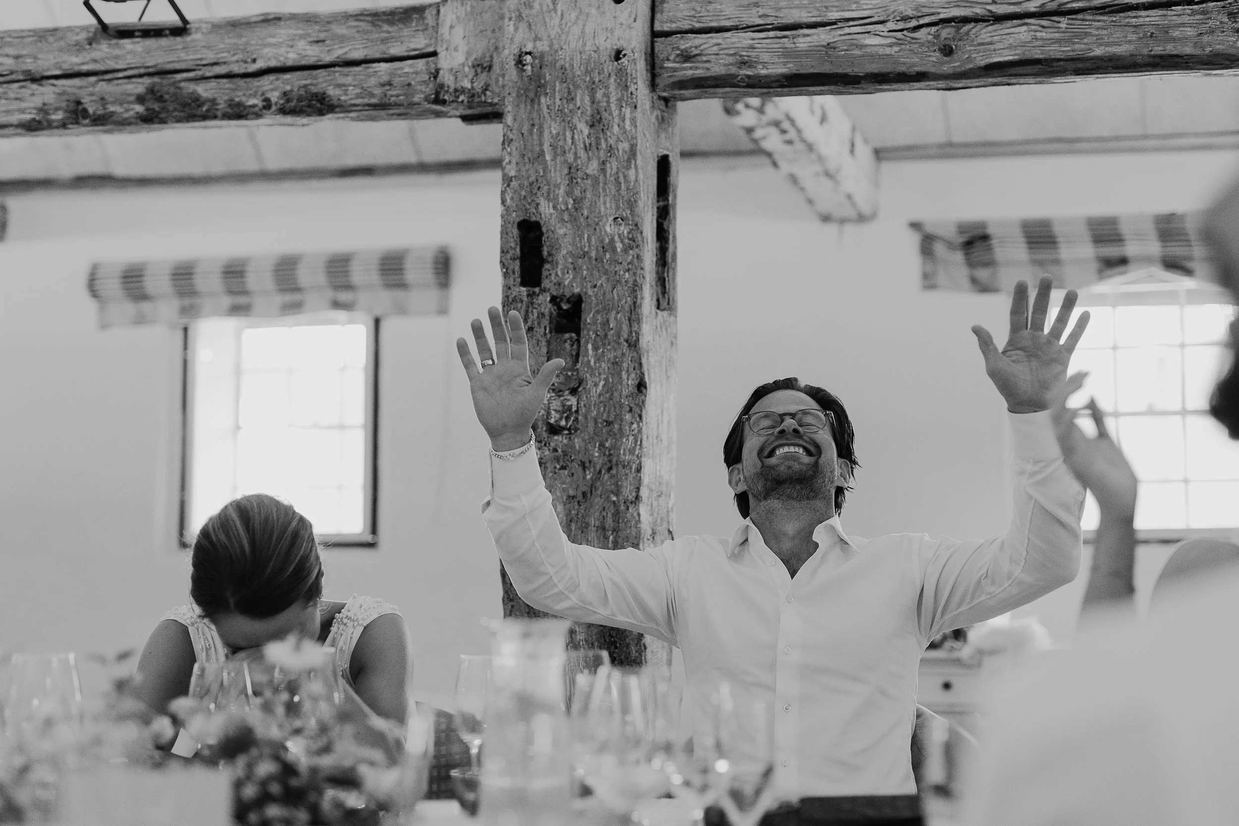 Mænd og kvinder i festlig anledning, der danser og hygger sig i et lyst rum med store vinduer, der sender naturligt lys ind.