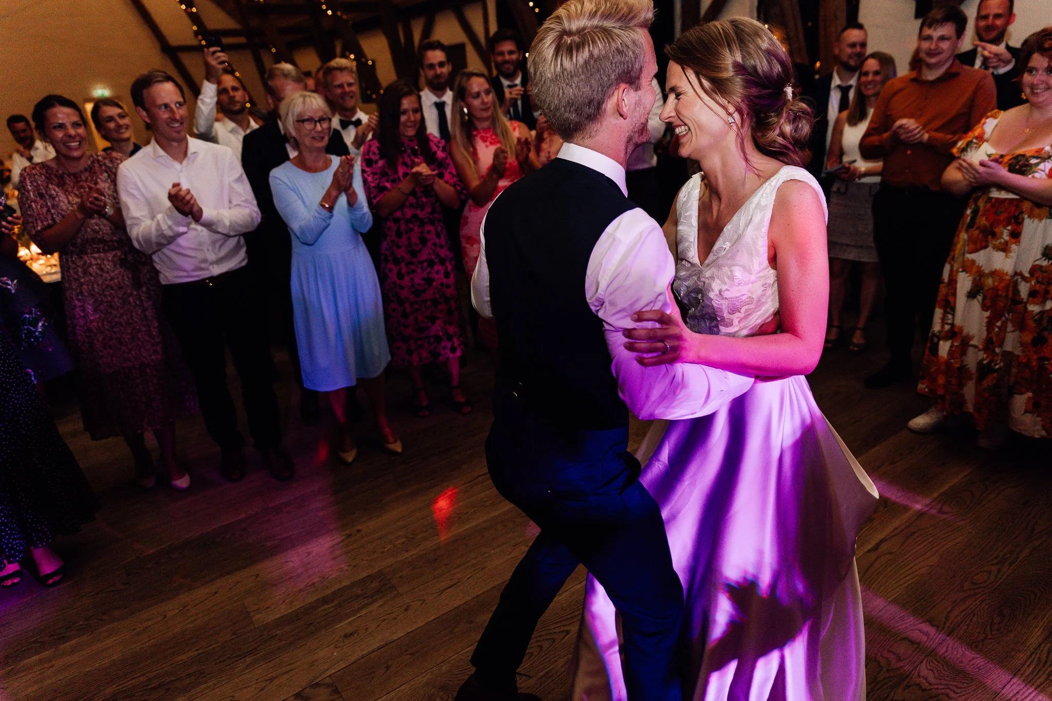 Et brudepar danser omringet af glade gæster til deres bryllupsfest.