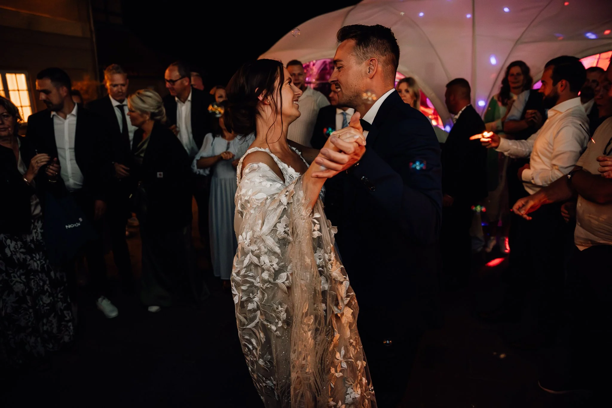 Et brudepar danser til en fest omgivet af festklædte mennesker