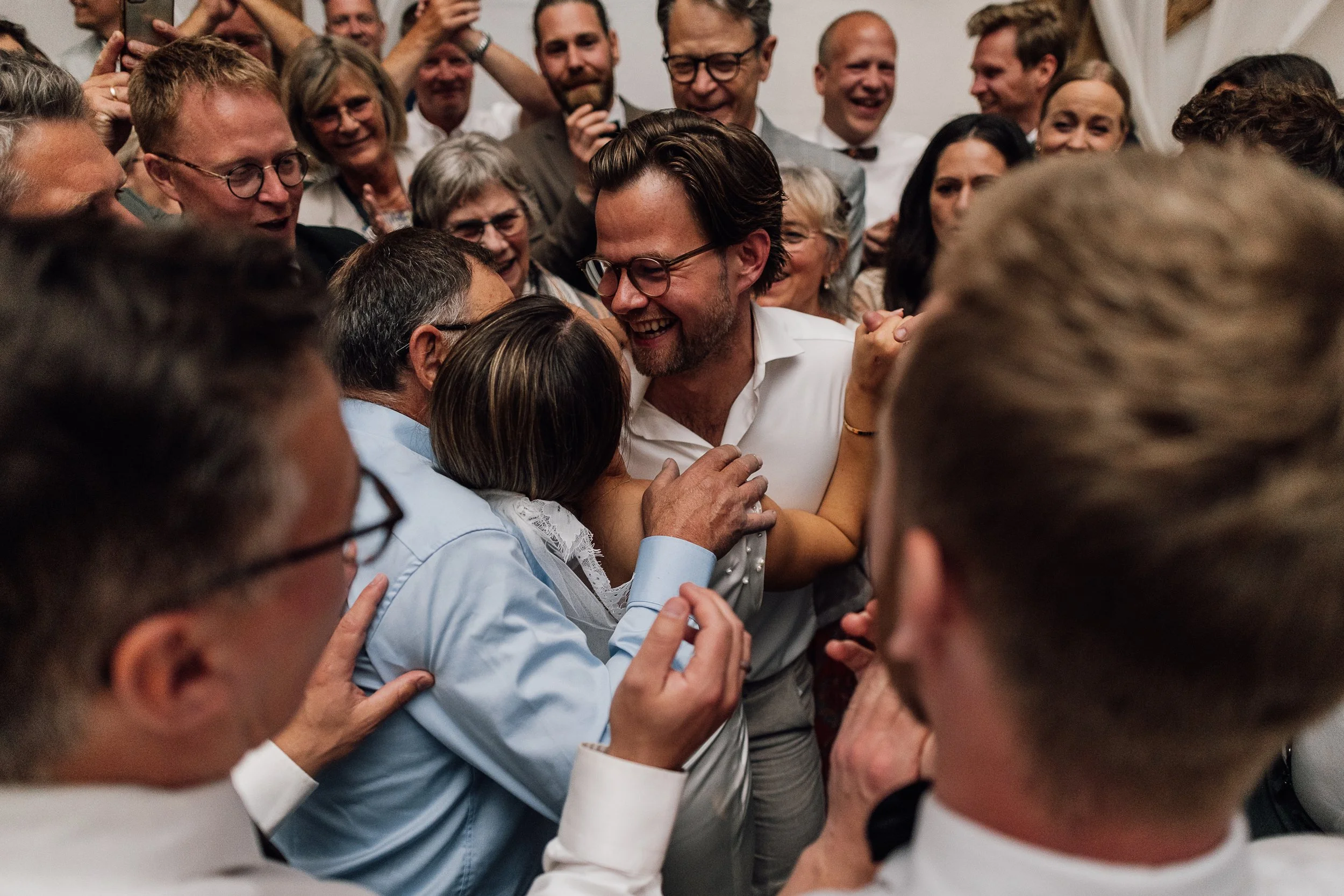 Brudepar i festlig atmosfære, smilende og krammende hinanden til bryllup