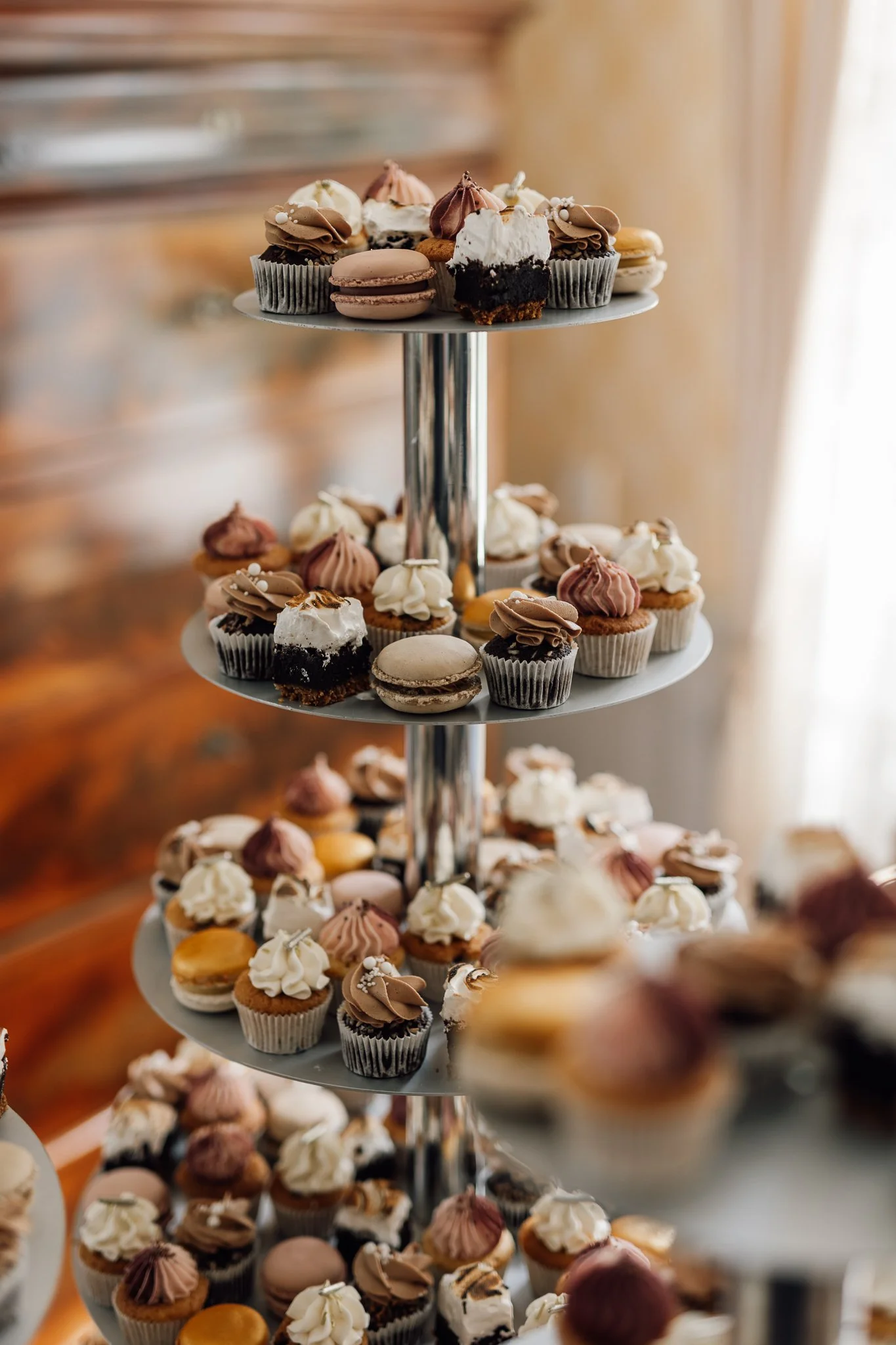 Et fler-etagers kagebord fyldt med forskellige små kager og cupcakes.