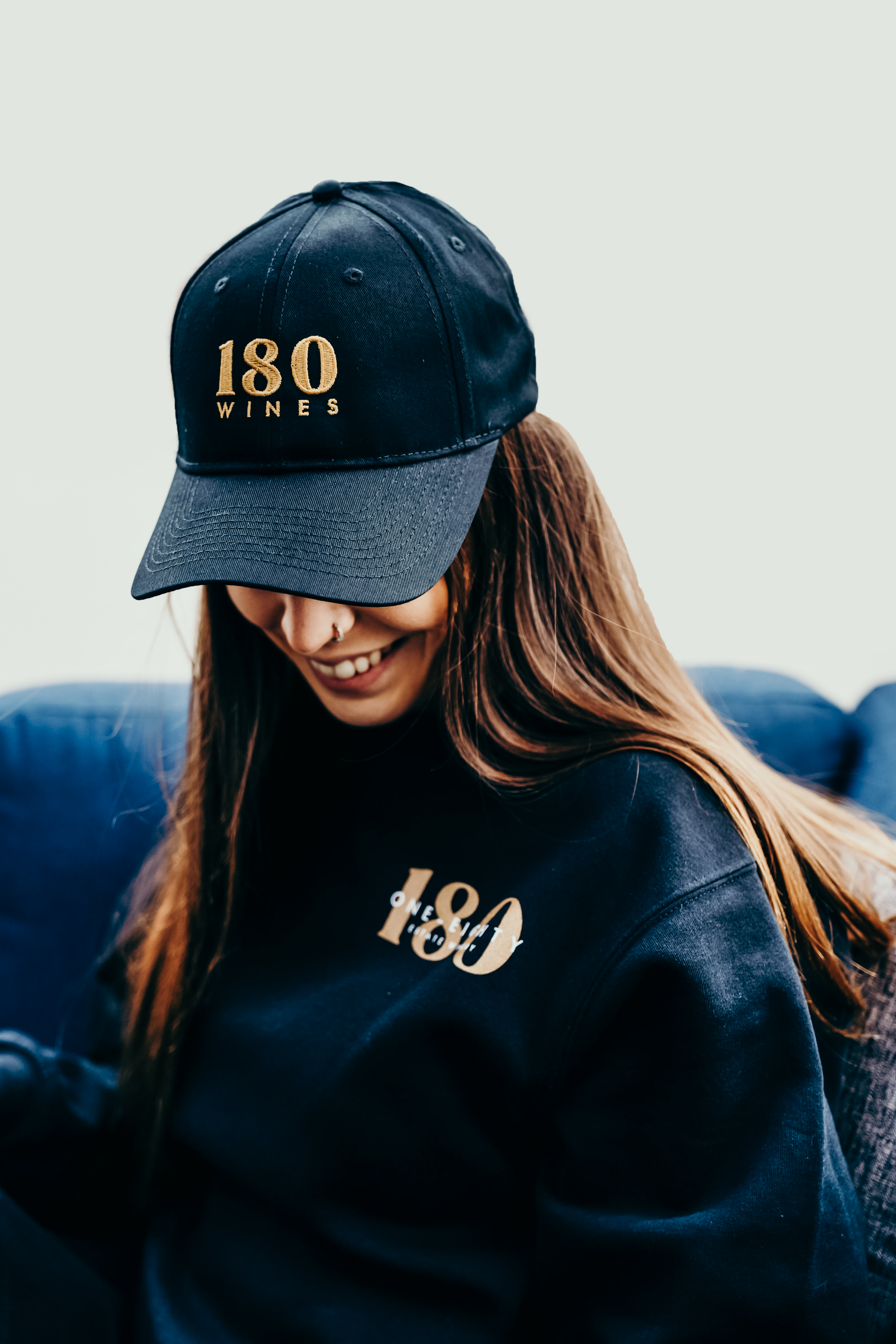 Girl wearing 180 cap in black with gold lettering and black 180 cozy crewneck in black.