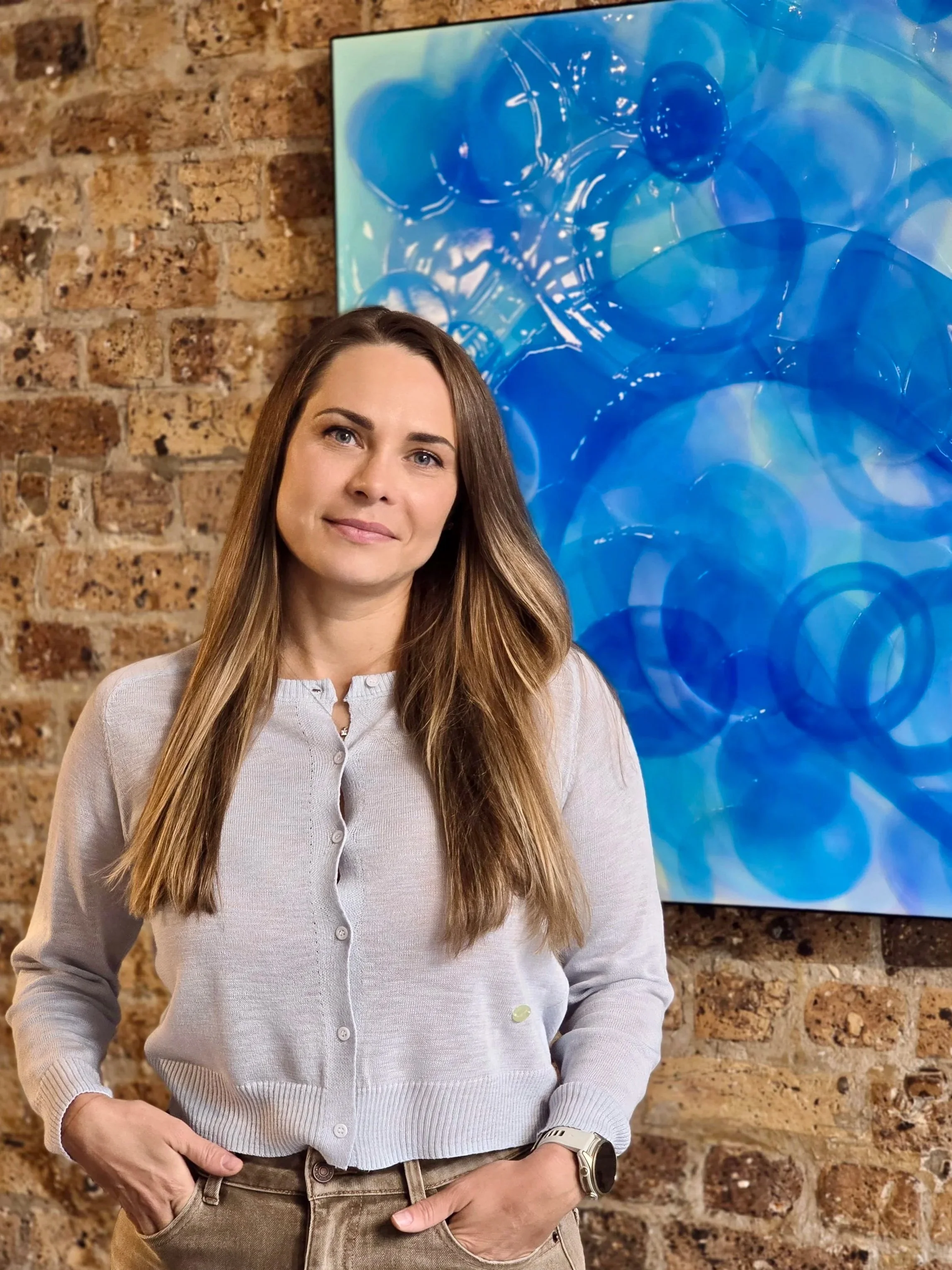 Artist Daria Baluta in front of her large-scale abstract epoxy resin artwork Cerulean