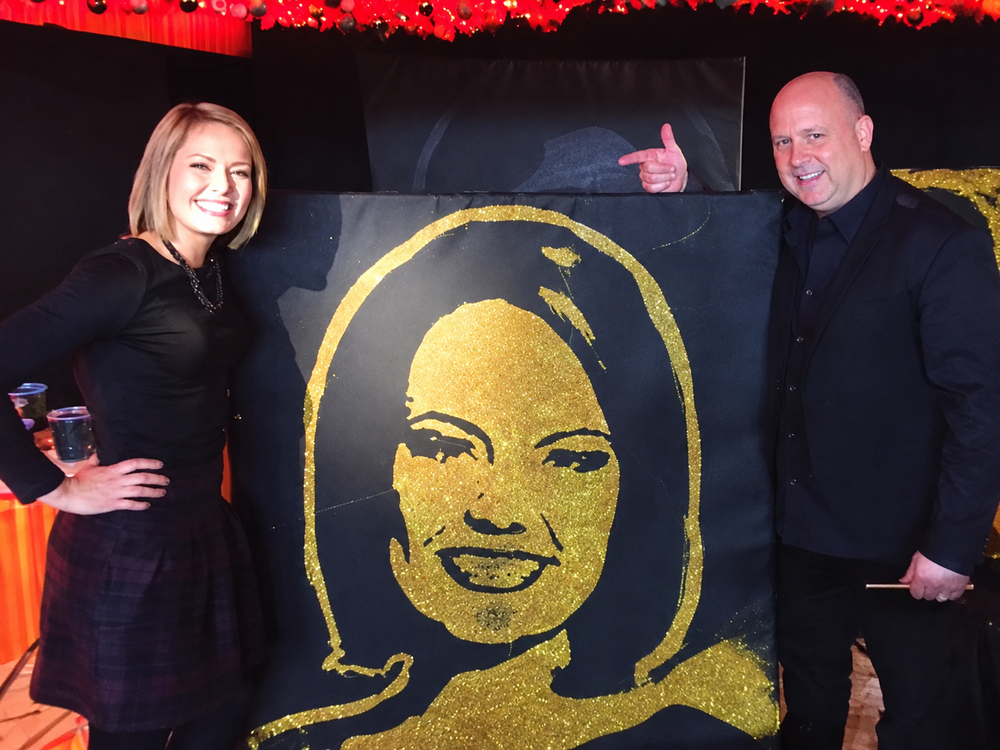 Robert Channing and [Name] with a gold glitter portrait
