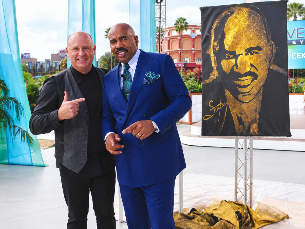 Robert Channing and Steve Harvey beside a gold glitter portrait