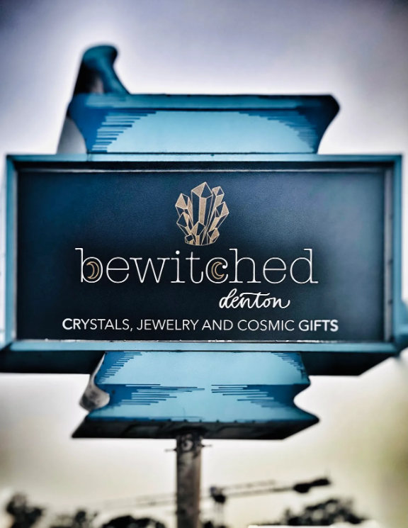 Sign for Bewitched Denton advertising crystals, jewelry, and cosmic gifts.