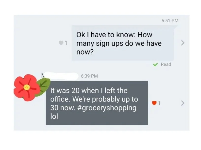 A screenshot of a chat conversation on a messaging app. The first message asks about the number of sign ups. The second message states that the number has increased from 20 to about 30 after grocery shopping, with a flower sticker and a heart reaction visible.