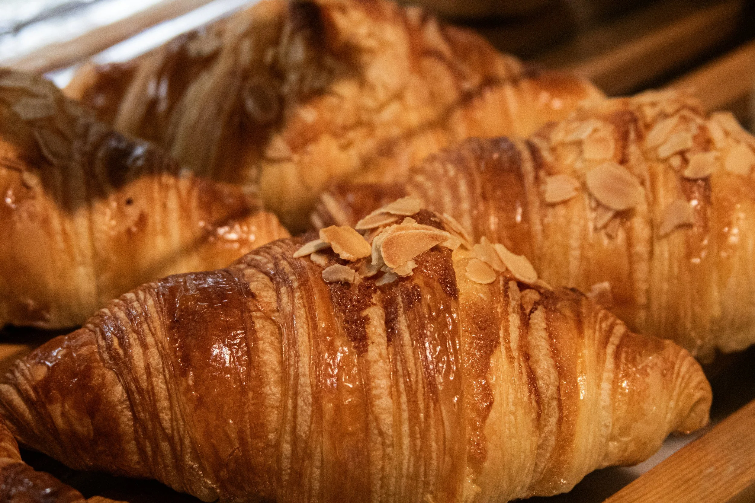 Close-up of a flaky, golden-brown pastry topped with sliced almonds.