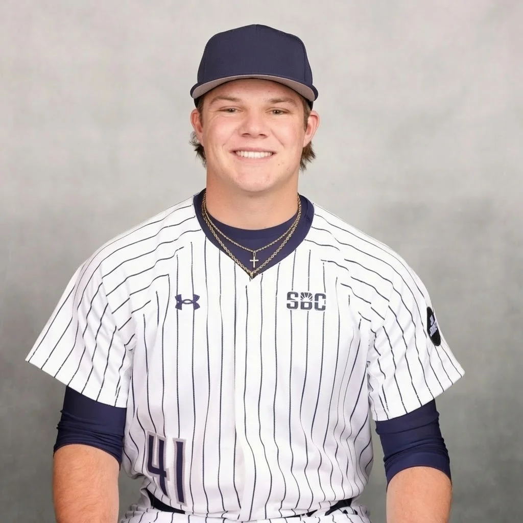 Young man in baseball uniform smiling, wearing a navy cap, white pinstriped jersey with numbers 41, and layered necklaces.