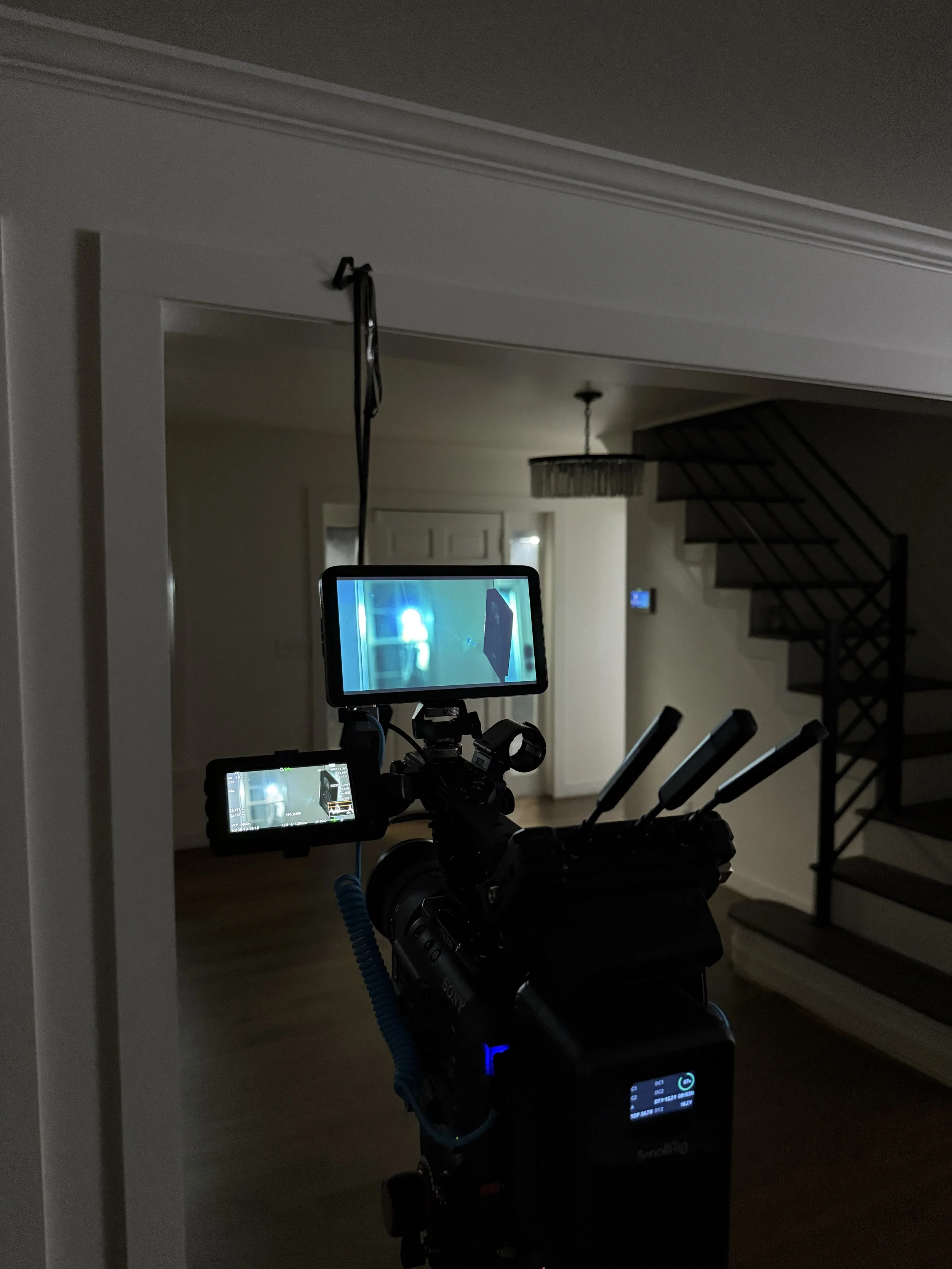 Camera mounted on a robotic rig aimed at a staircase in a dimly lit home interior.