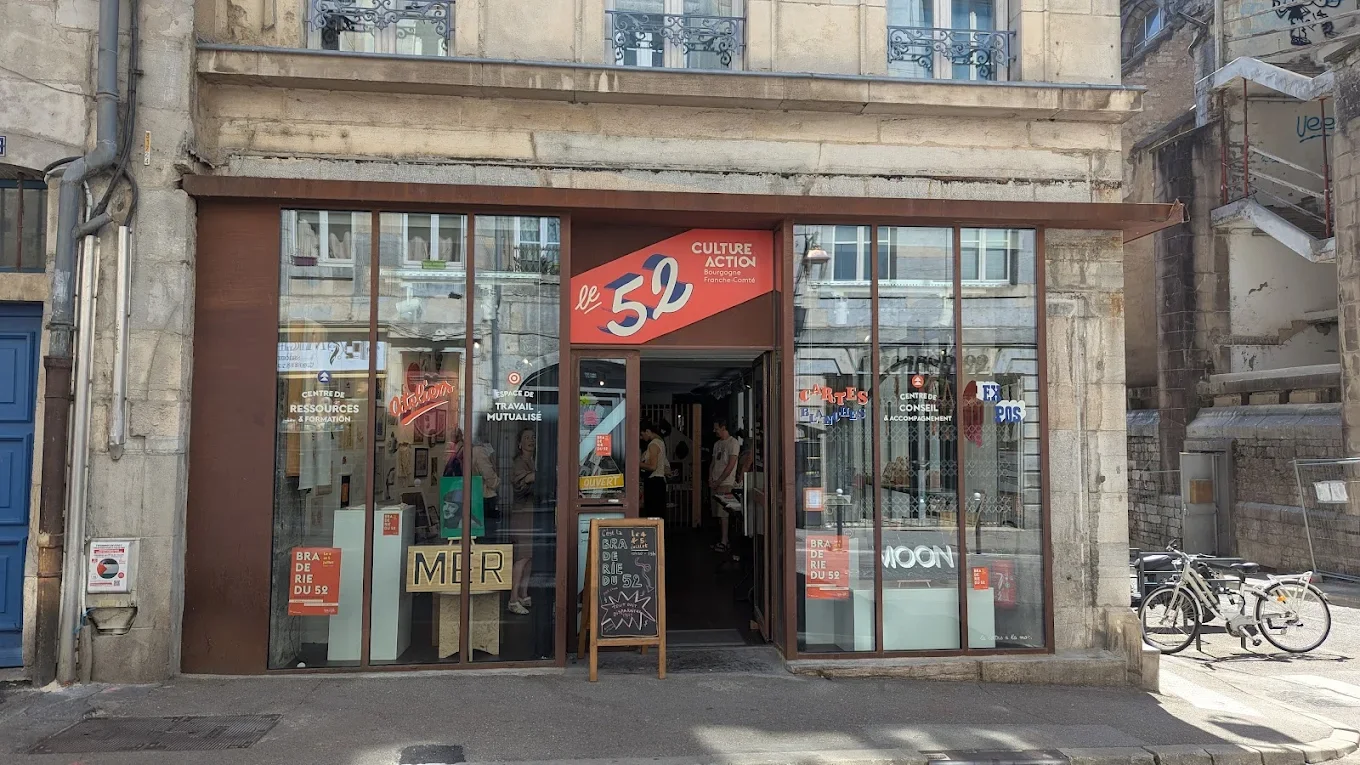 Façade d'un centre culturel avec vitrines, le 52 à Besançon , et personnes à l'intérieur.