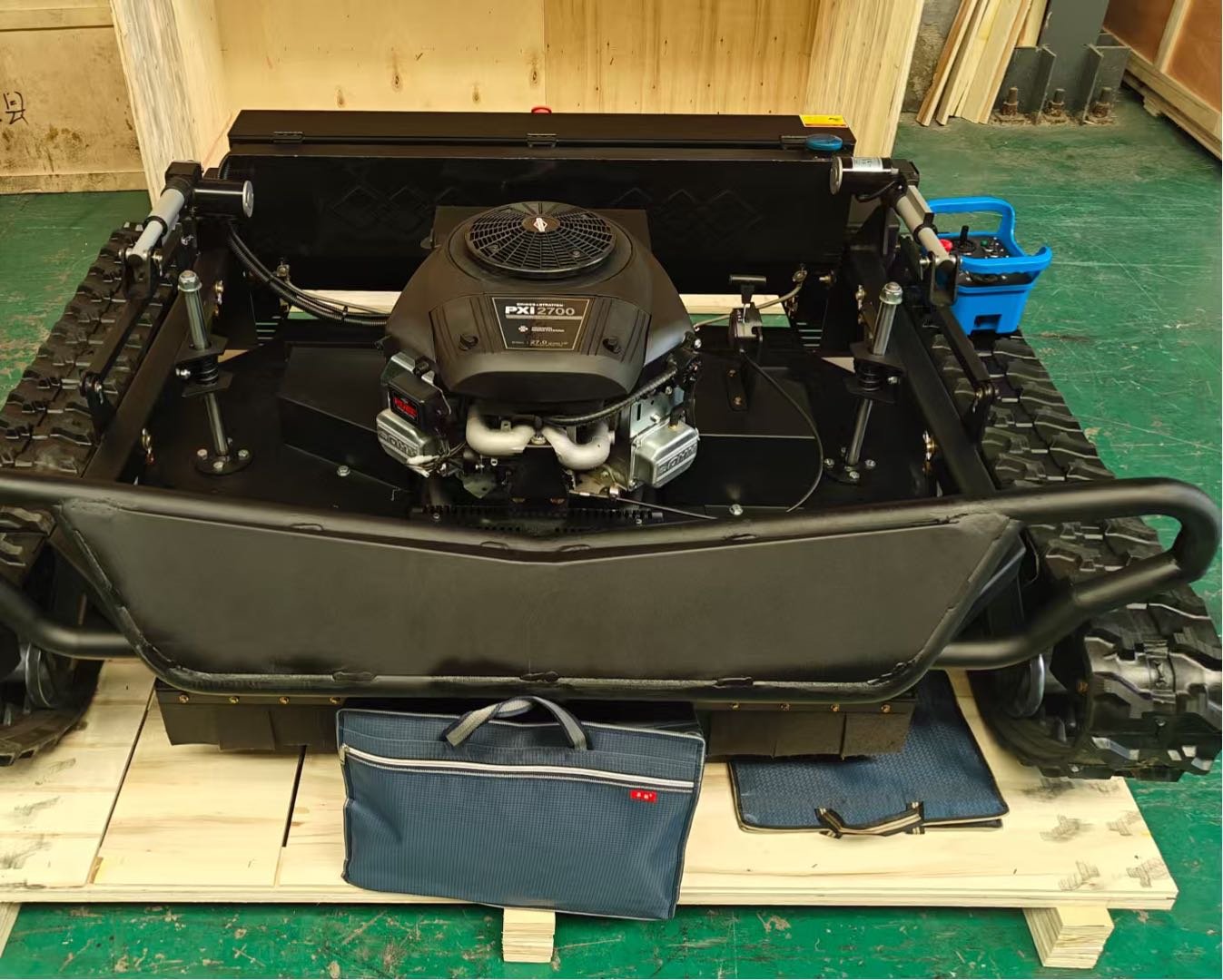 A tracked robotic vehicle with a Honda PXI 2700 engine, displayed on a wooden pallet in a workshop.