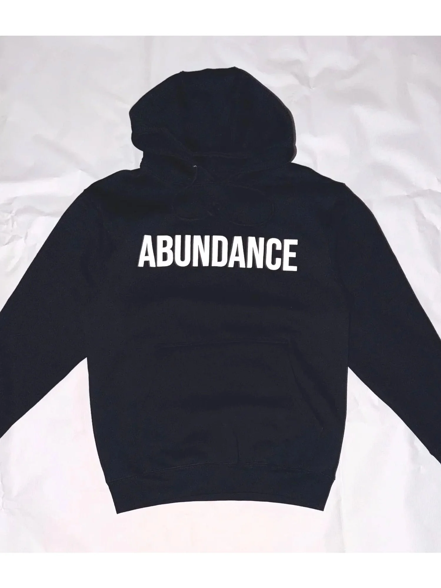 Black hoodie with the word 'ABUNDANCE' written in white capital letters on the front.