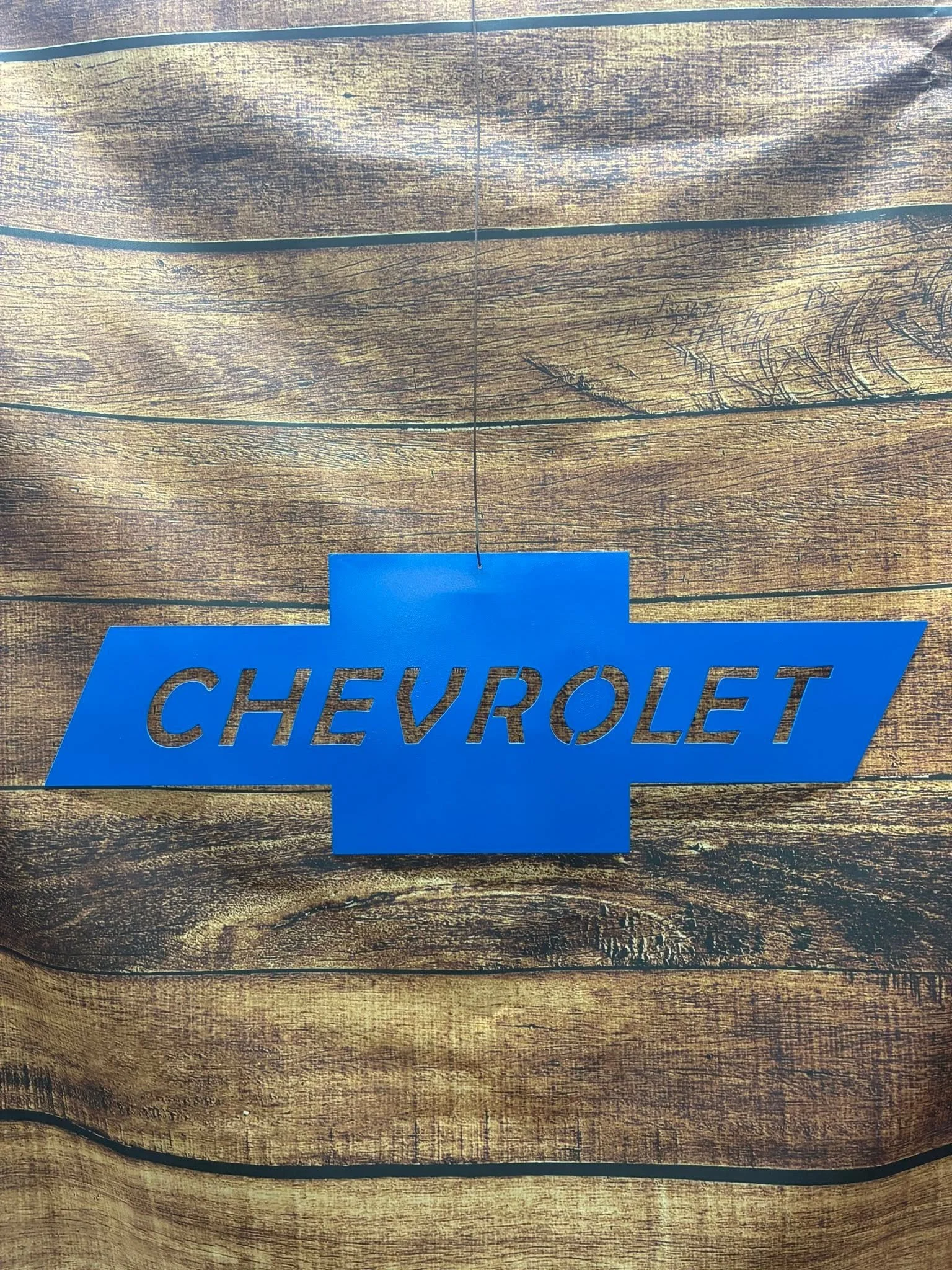 A wooden surface with a Chevrolet logo sign in blue.