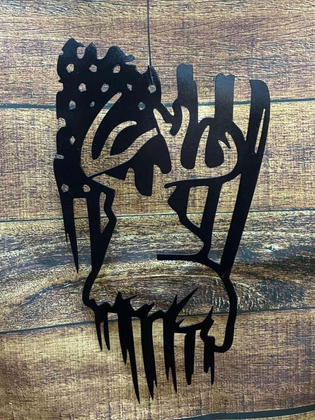 Black metal wall art with a mountain scene and the word 'Colorado' in cursive, hanging on a wooden wall.
