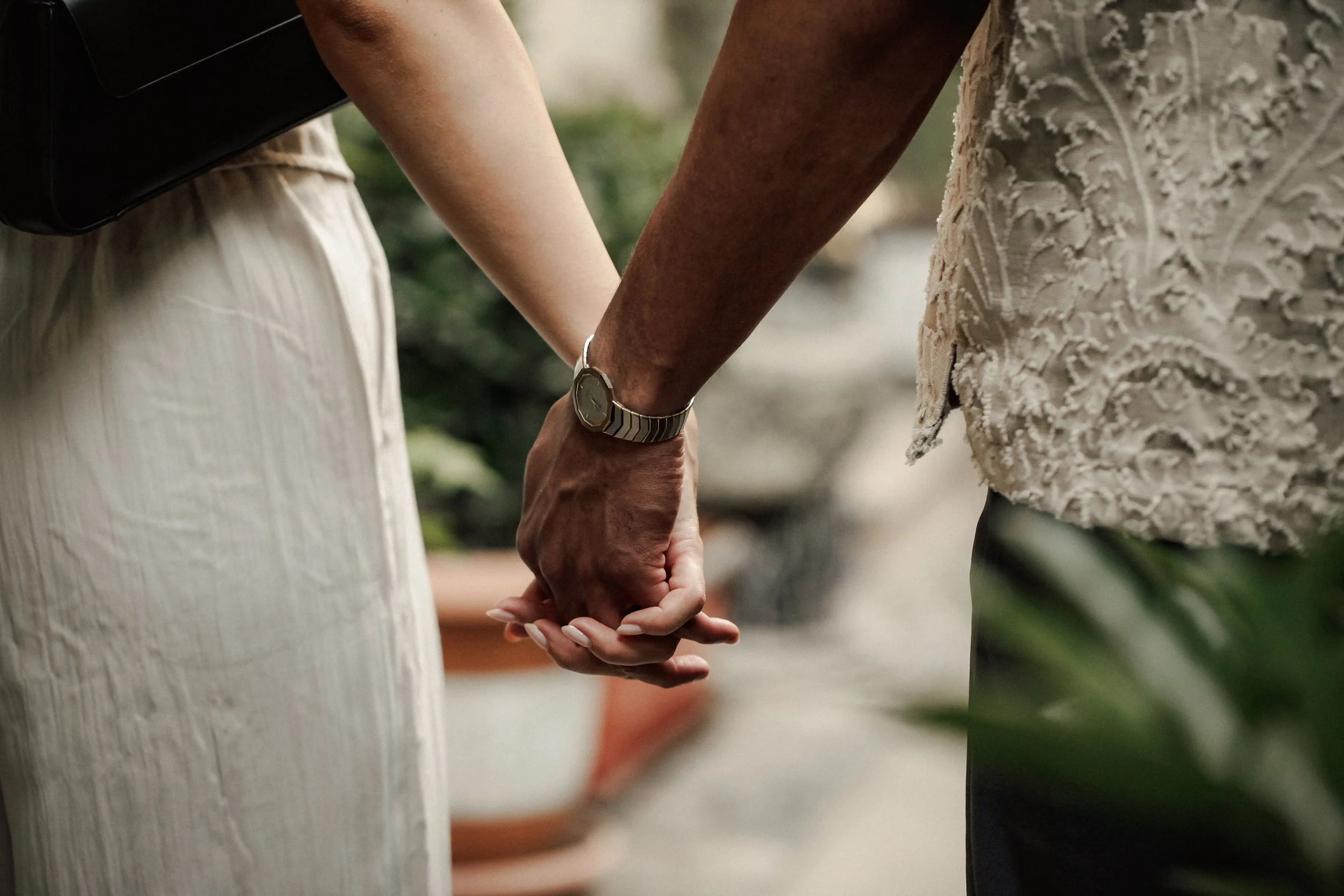 Close-up of two people holding hands during a procession or wedding ceremony.