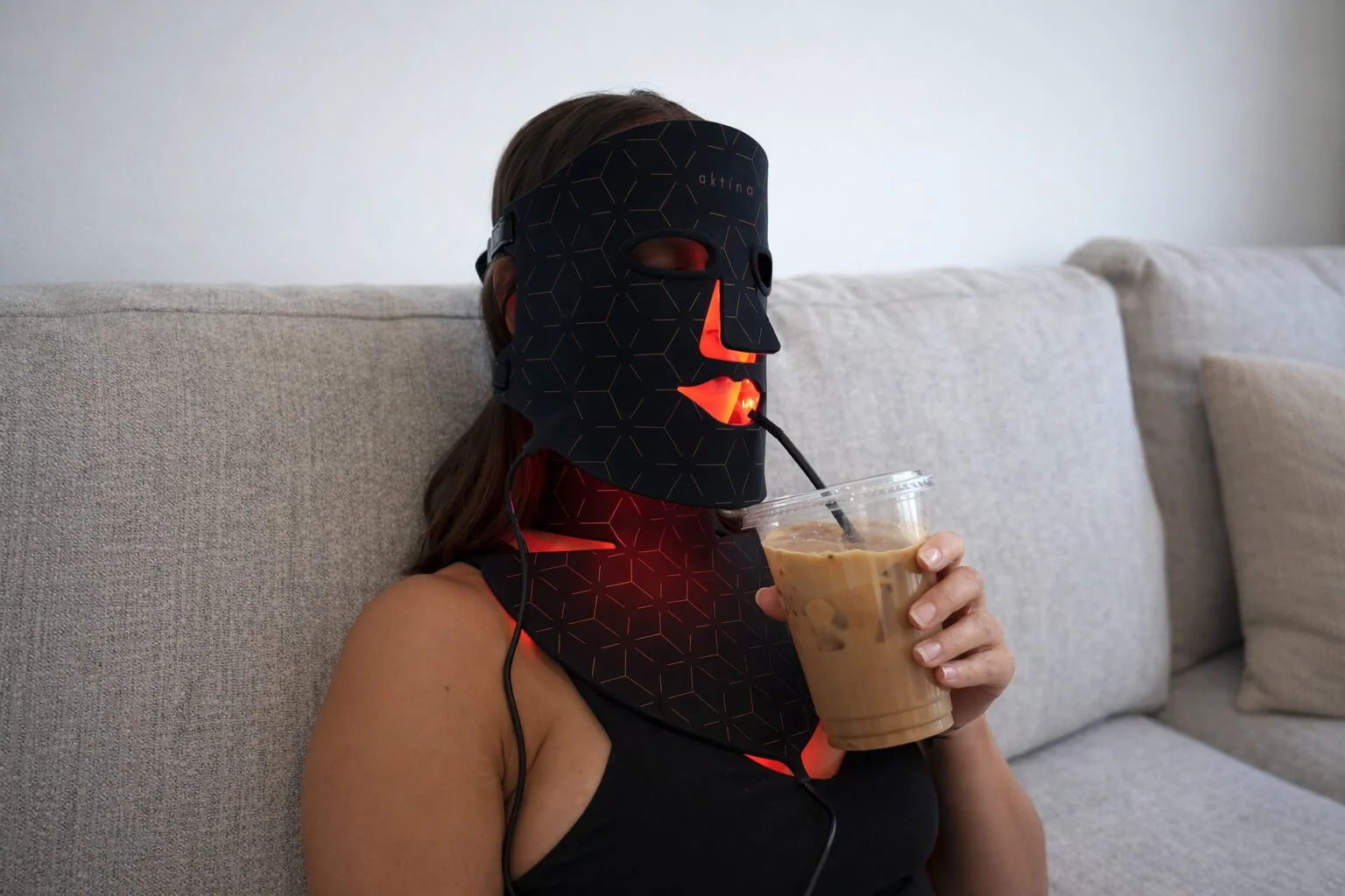 aktina Mask Red Light Drinking Iced Coffee on Couch.jpg
