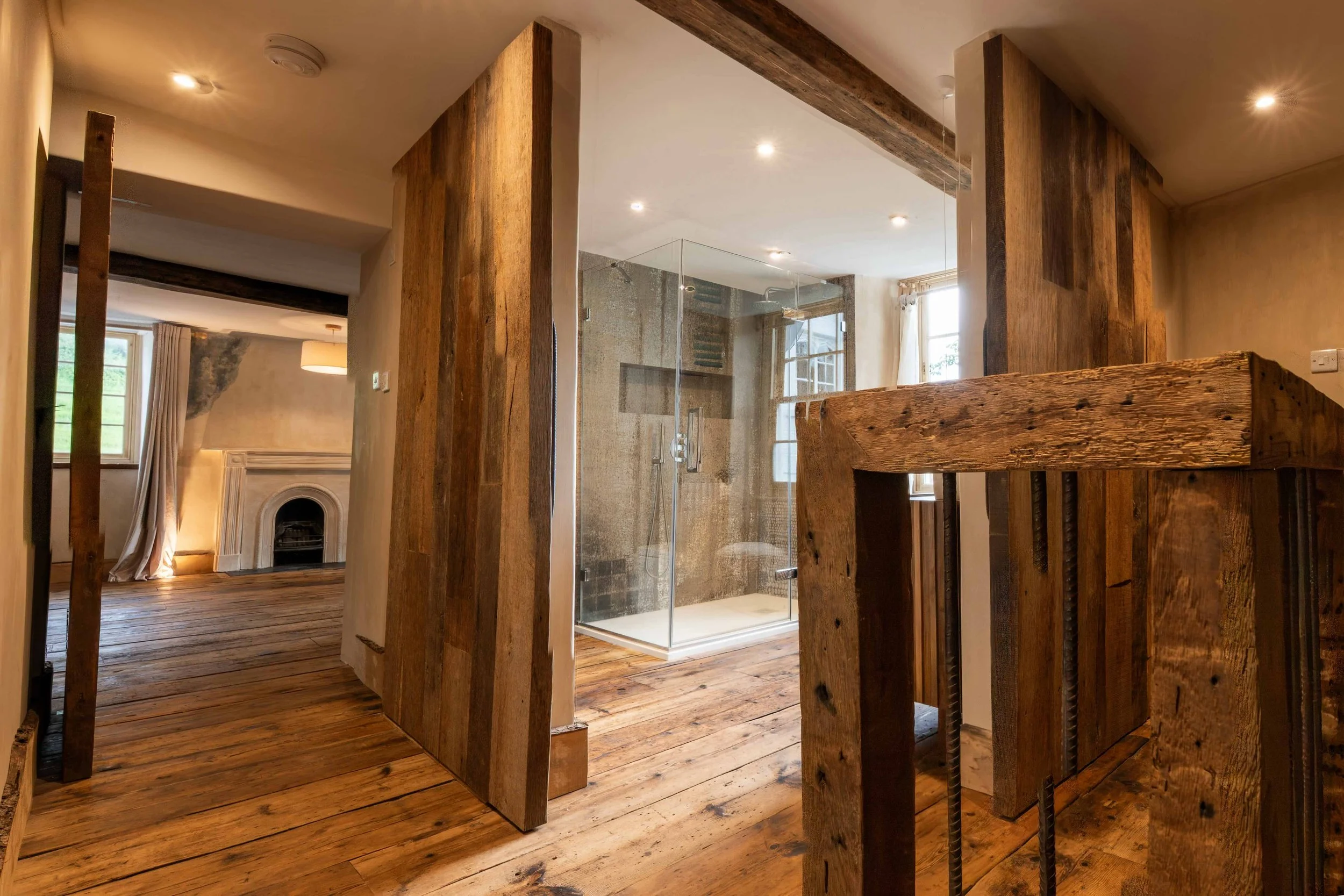 View through the interconnected rooms of the Editorial Suite, showing historic timber floors, beams, aged plaster and the fireplace beyond.