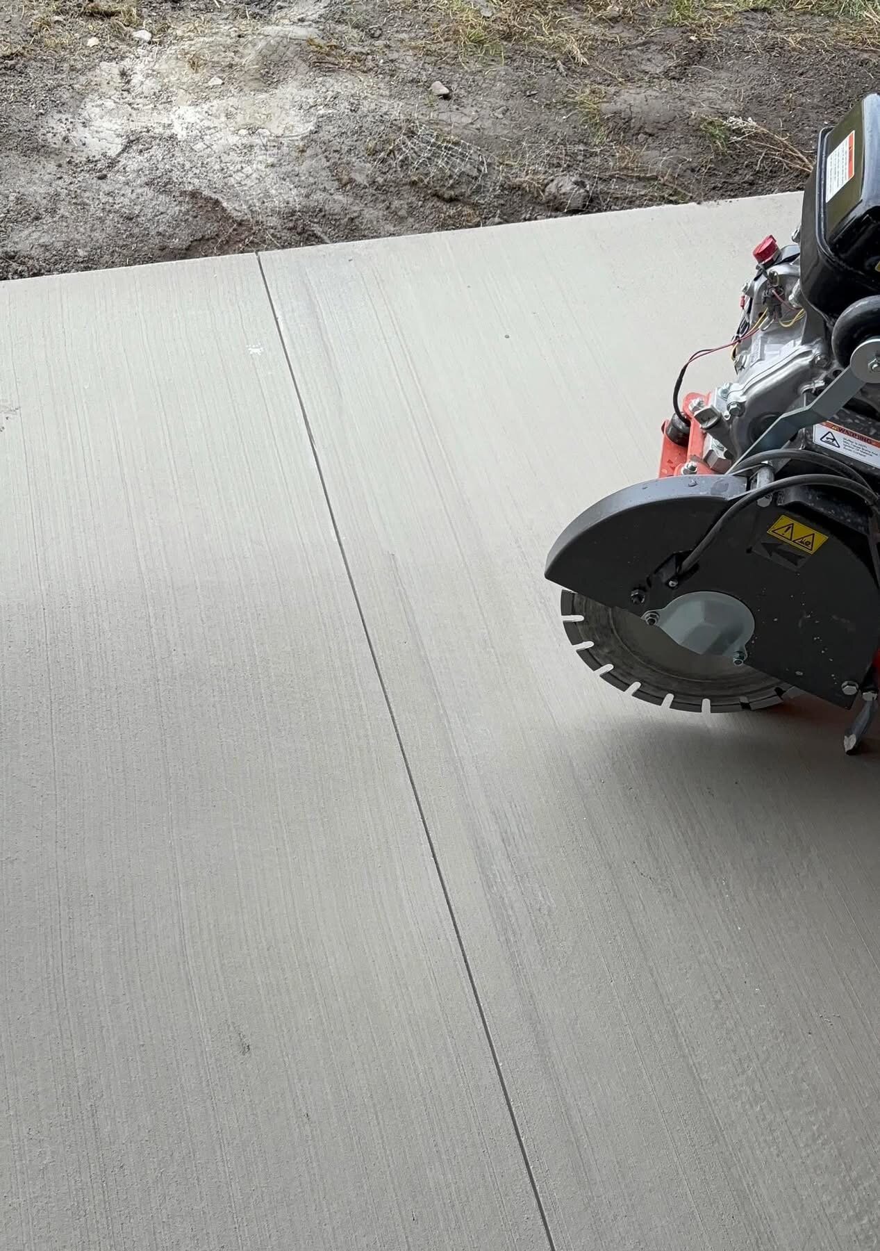 Walk-behind saw cutting control joints into a cured concrete slab to control cracking